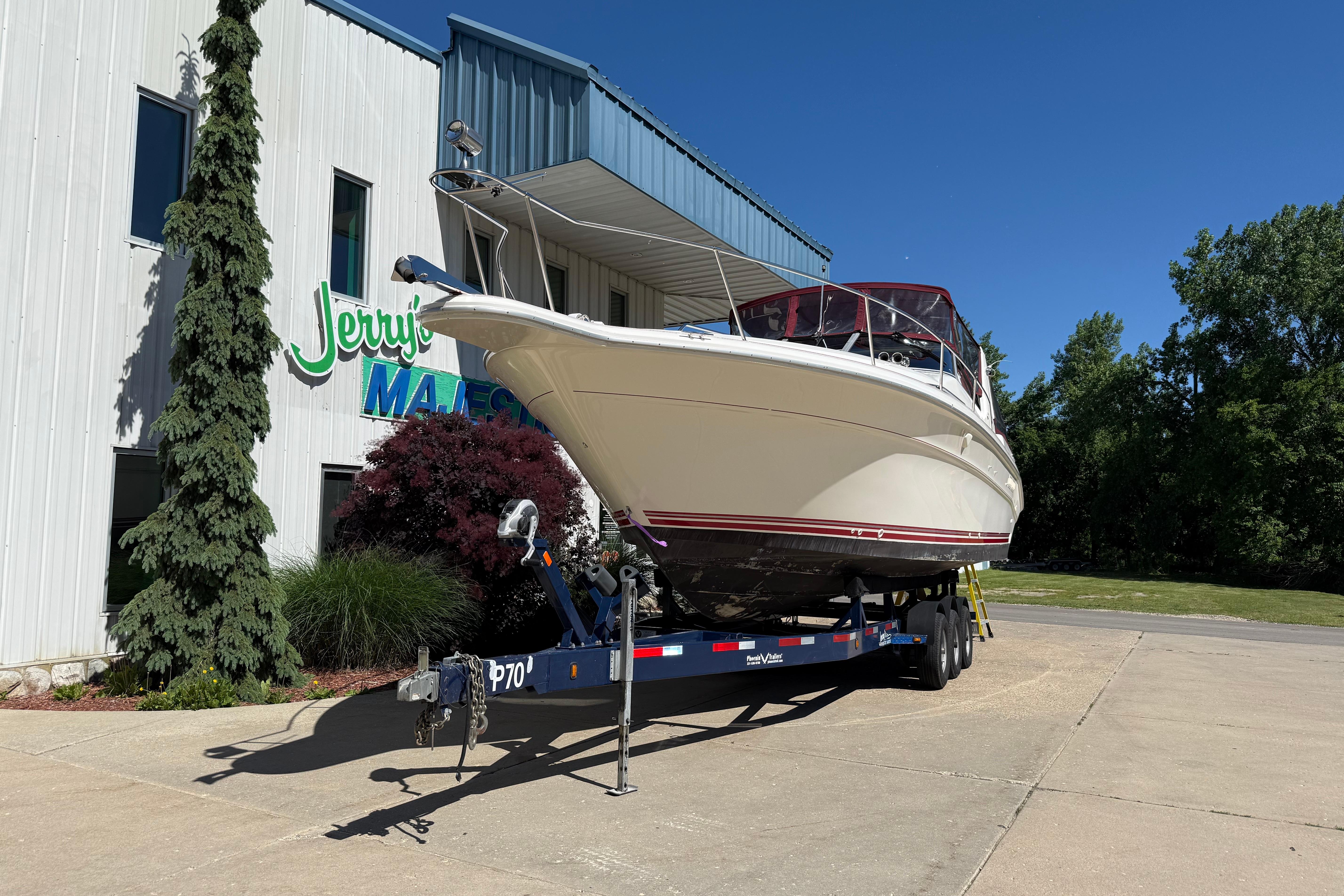 1990 Sea Ray 310 Express Cruiser on trailer outside building, clear sky background.