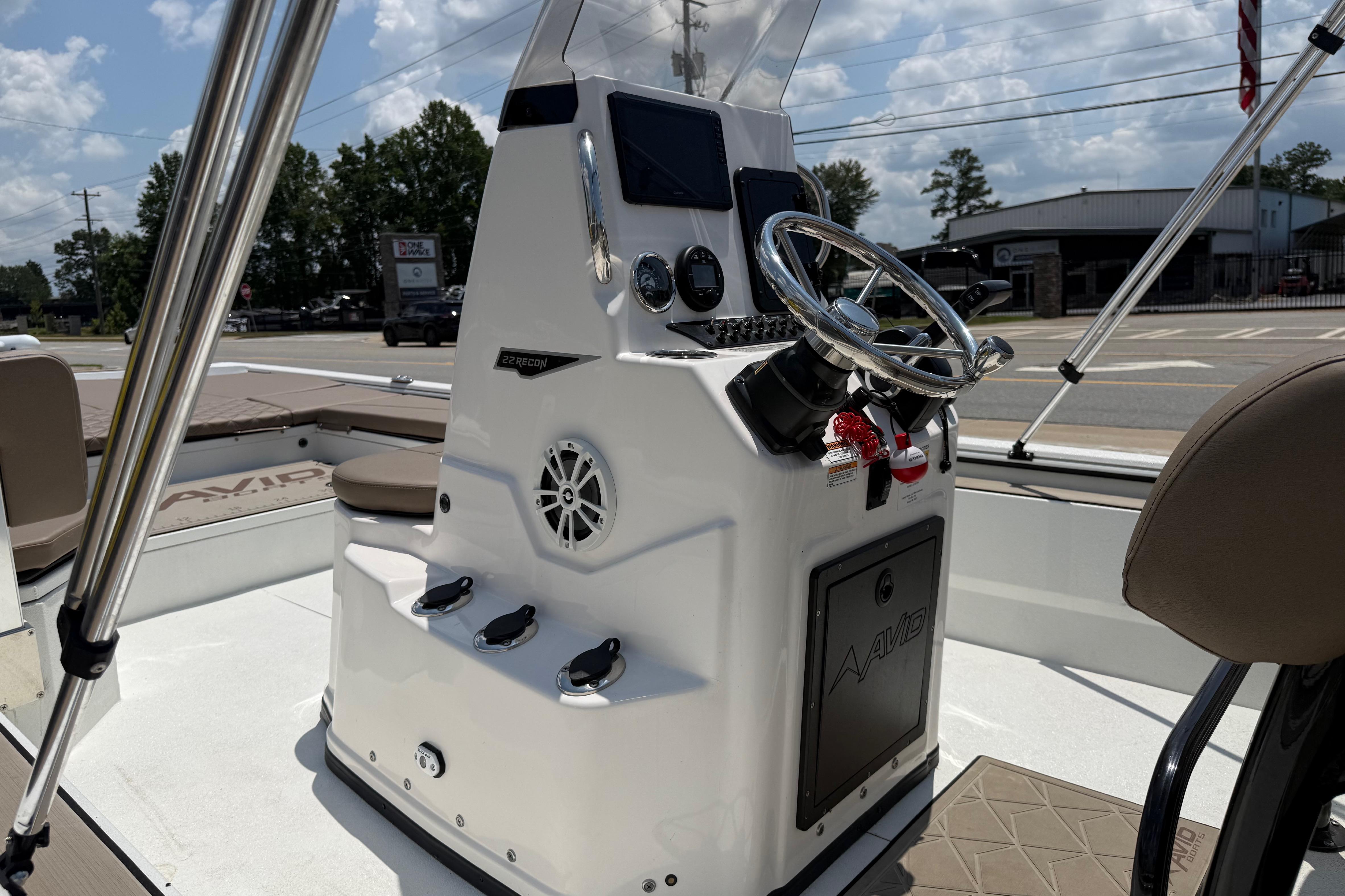 2025 Avid 22 Recon boat console with steering wheel and controls under a sunny sky.