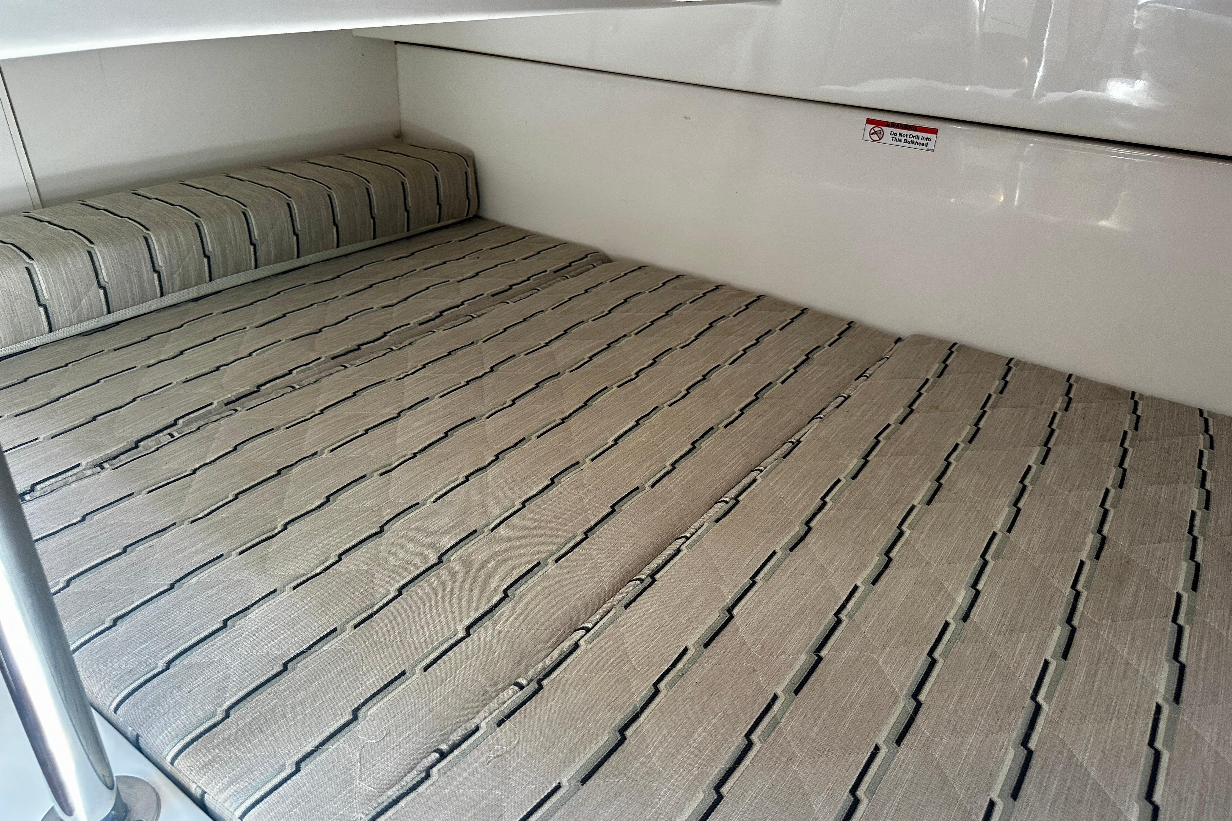 2019 Pursuit OS 325 Offshore cabin interior with striped bedding and sleek design.
