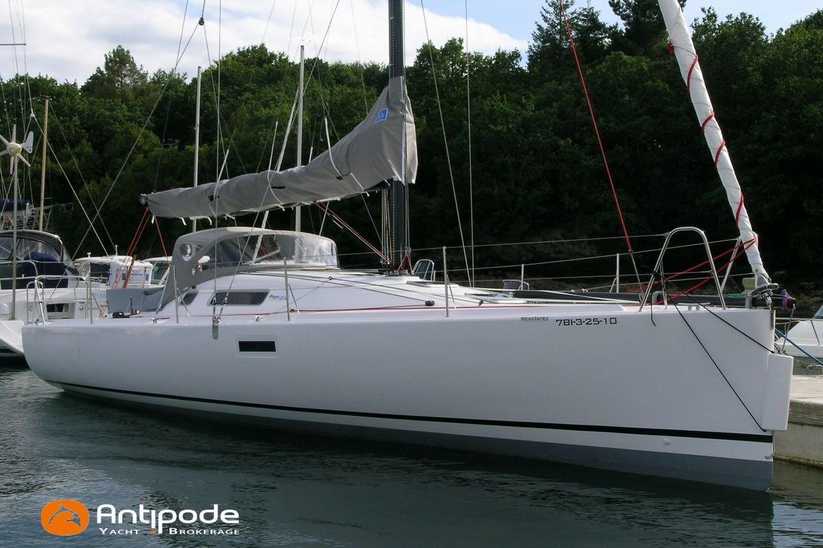 Sailing yacht Pogo 1050, 2010 model, docked at marina with lush green backdrop.