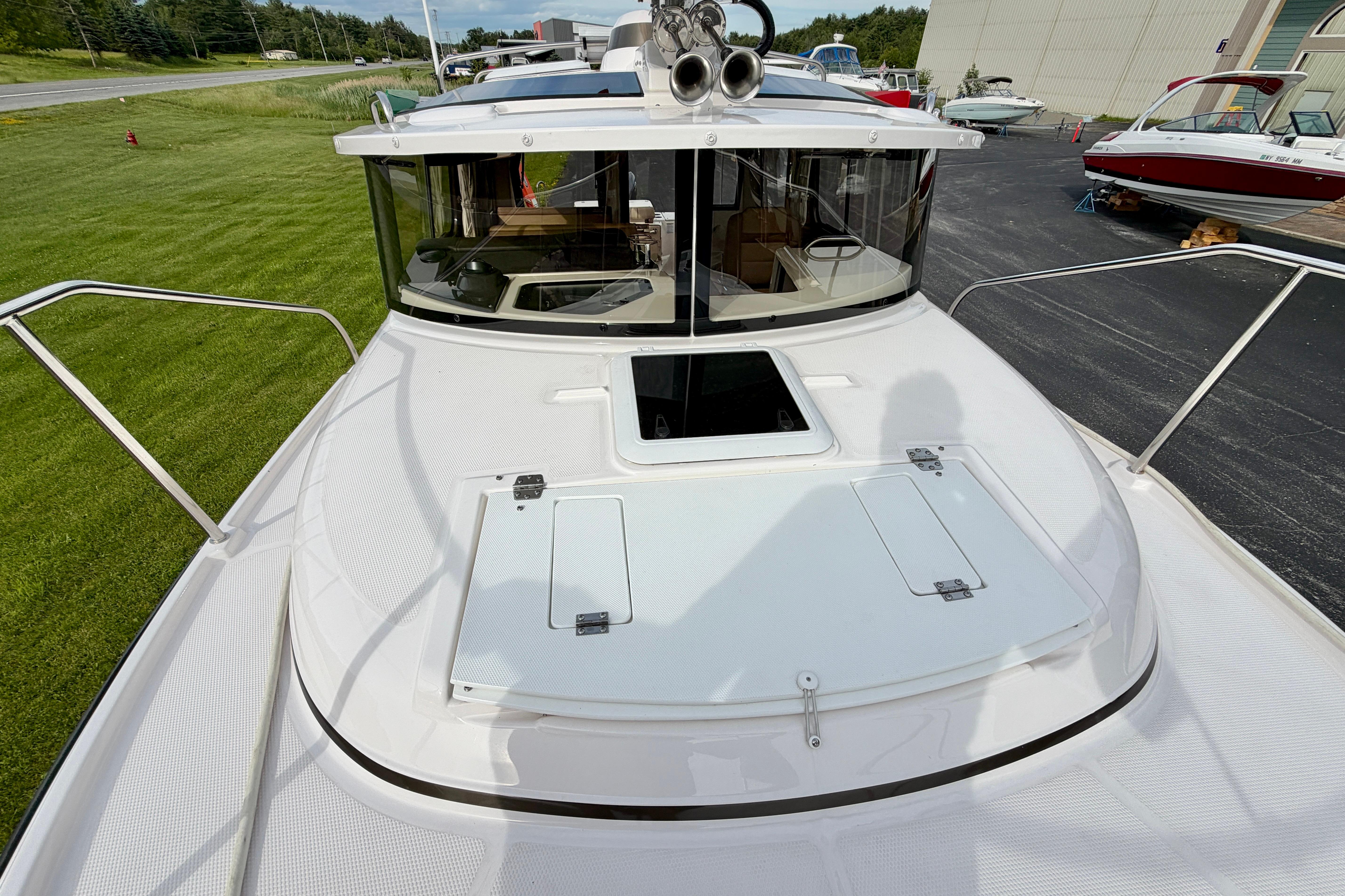 2025 Ranger Tugs R-27 boat deck with hatch, docked near grassy area.