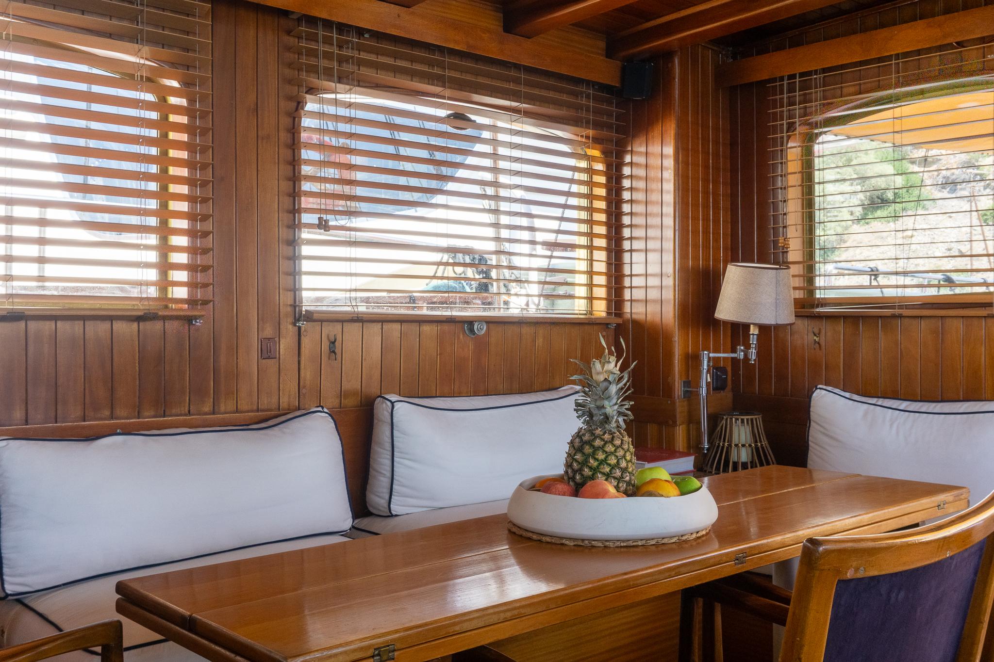 Interior of 1969 Custom Psarros Shipyard yacht with wooden decor and fruit centerpiece.