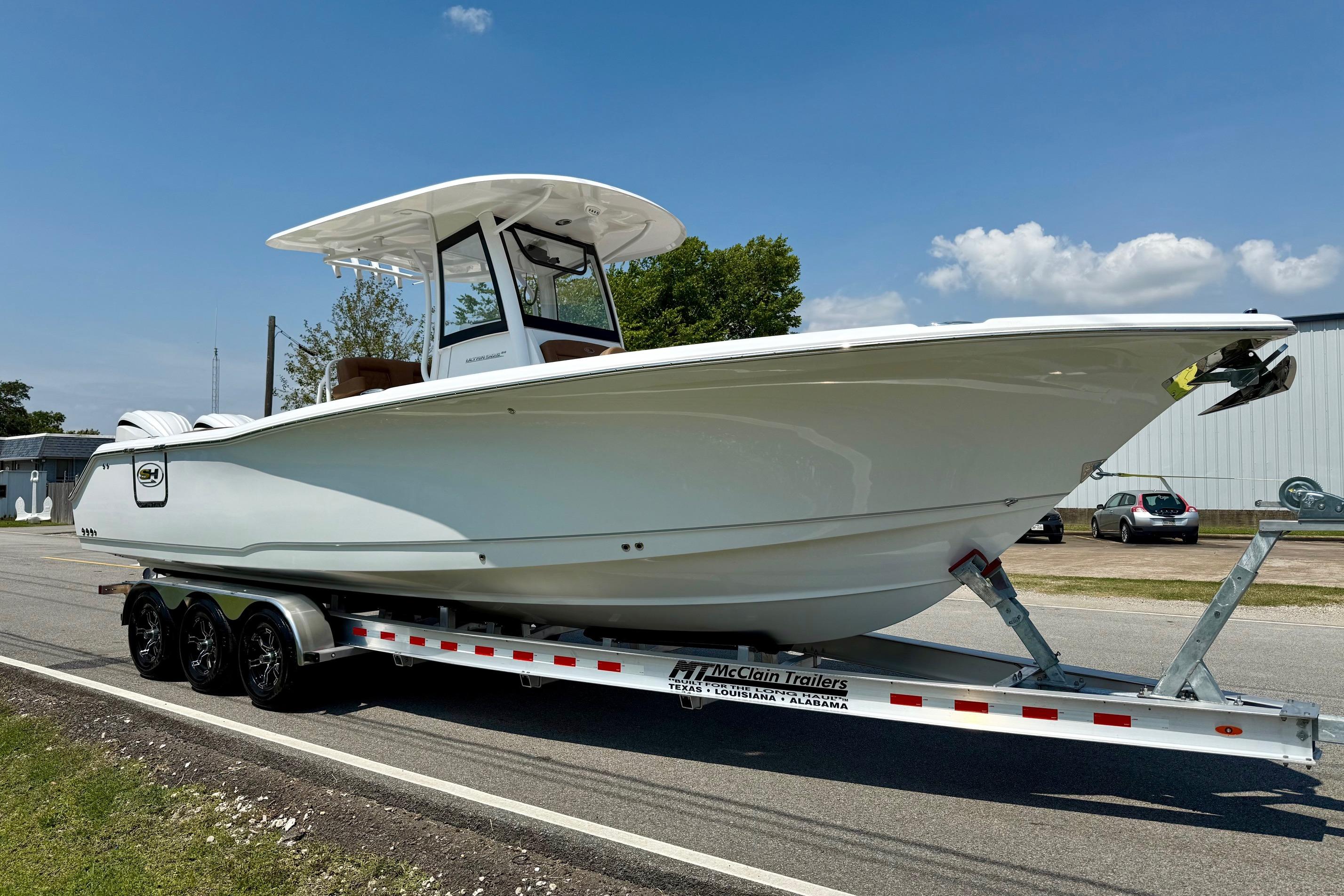 2026 Sea Hunt Ultra 305 SE boat on trailer, parked on roadside under clear sky.
