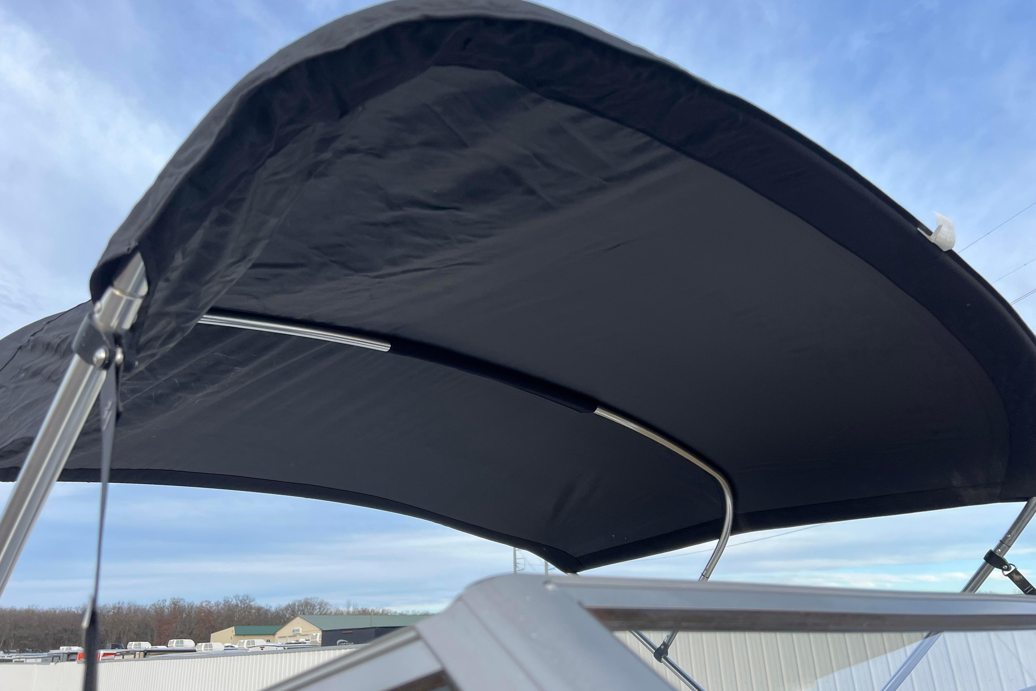 2013 Larson LX 205S IO boat with black bimini top against blue sky.