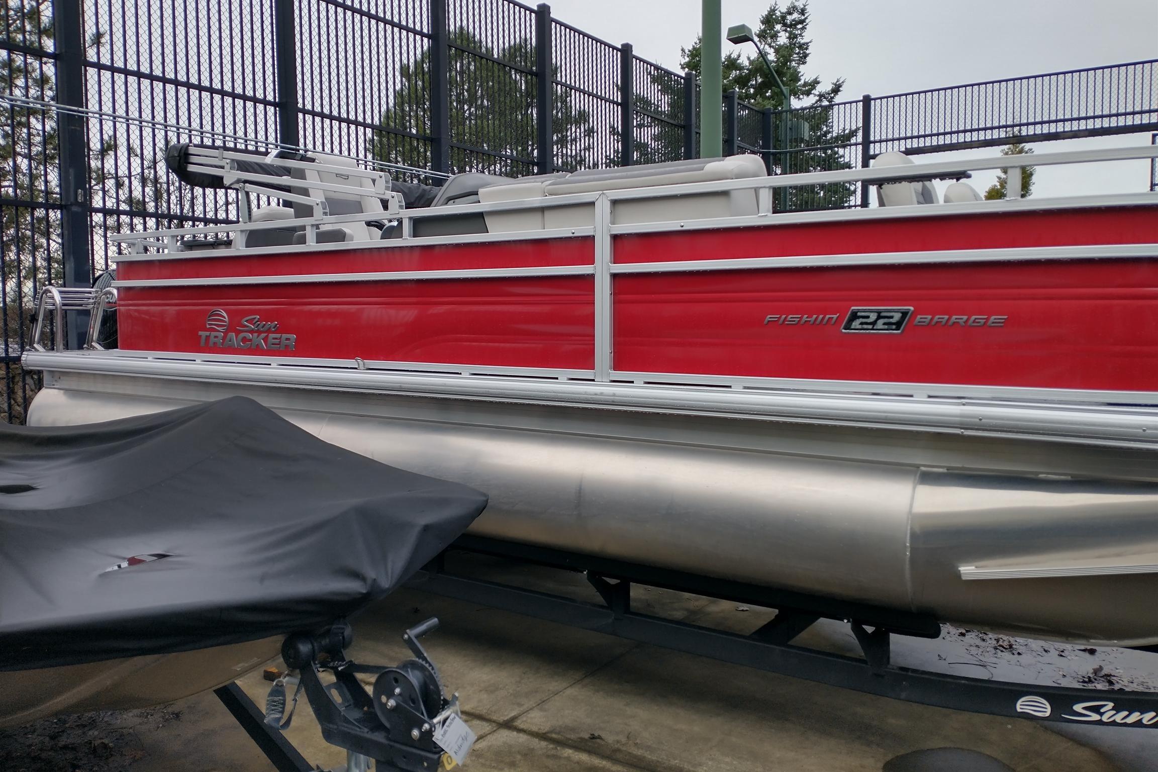 2026 Sun Tracker Fishin' Barge 22 DLX pontoon boat, red exterior, parked outdoors.