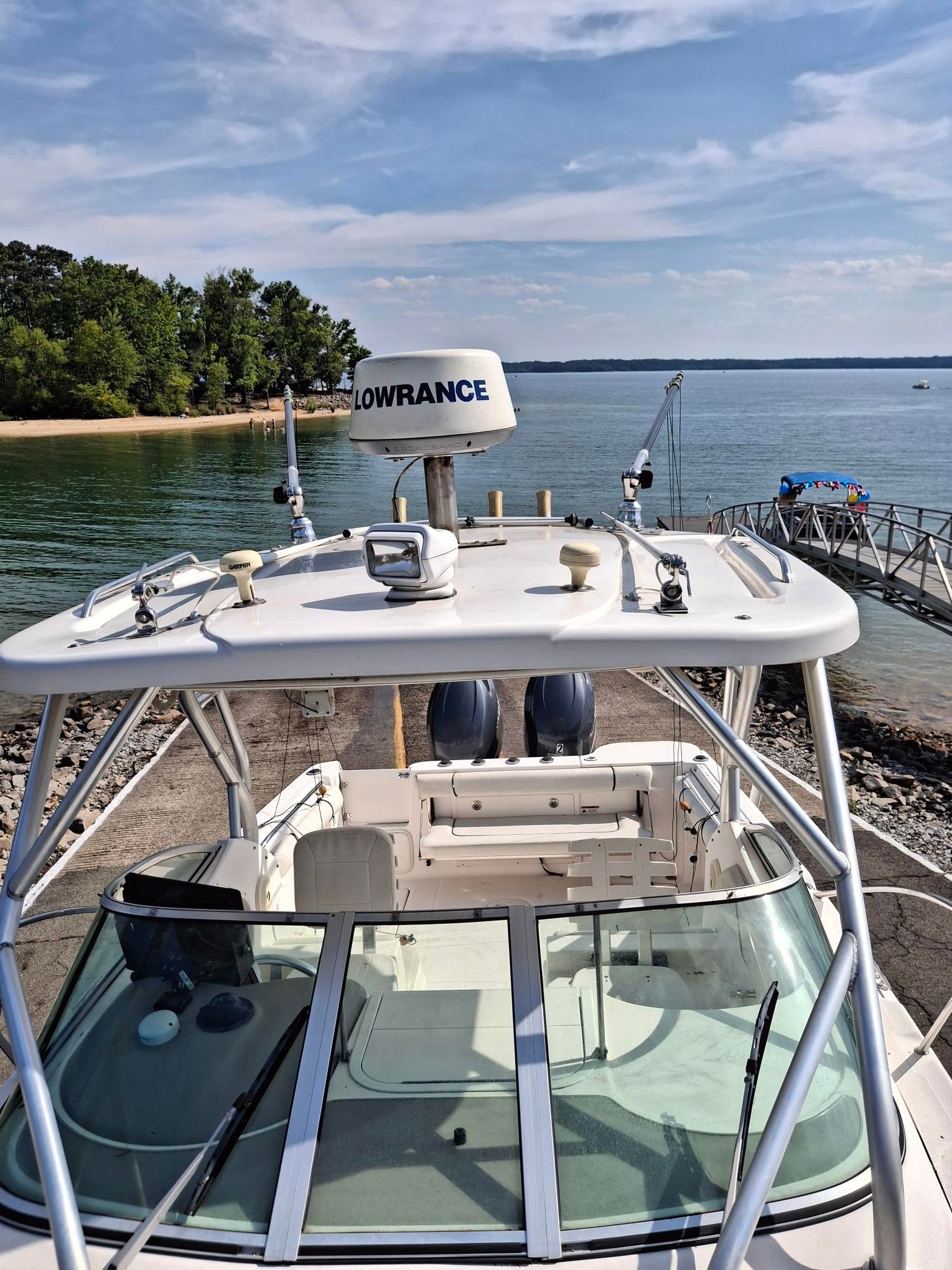 A 2008 Wellcraft 252 Coastal boat is docked by a calm lake under a clear sky.