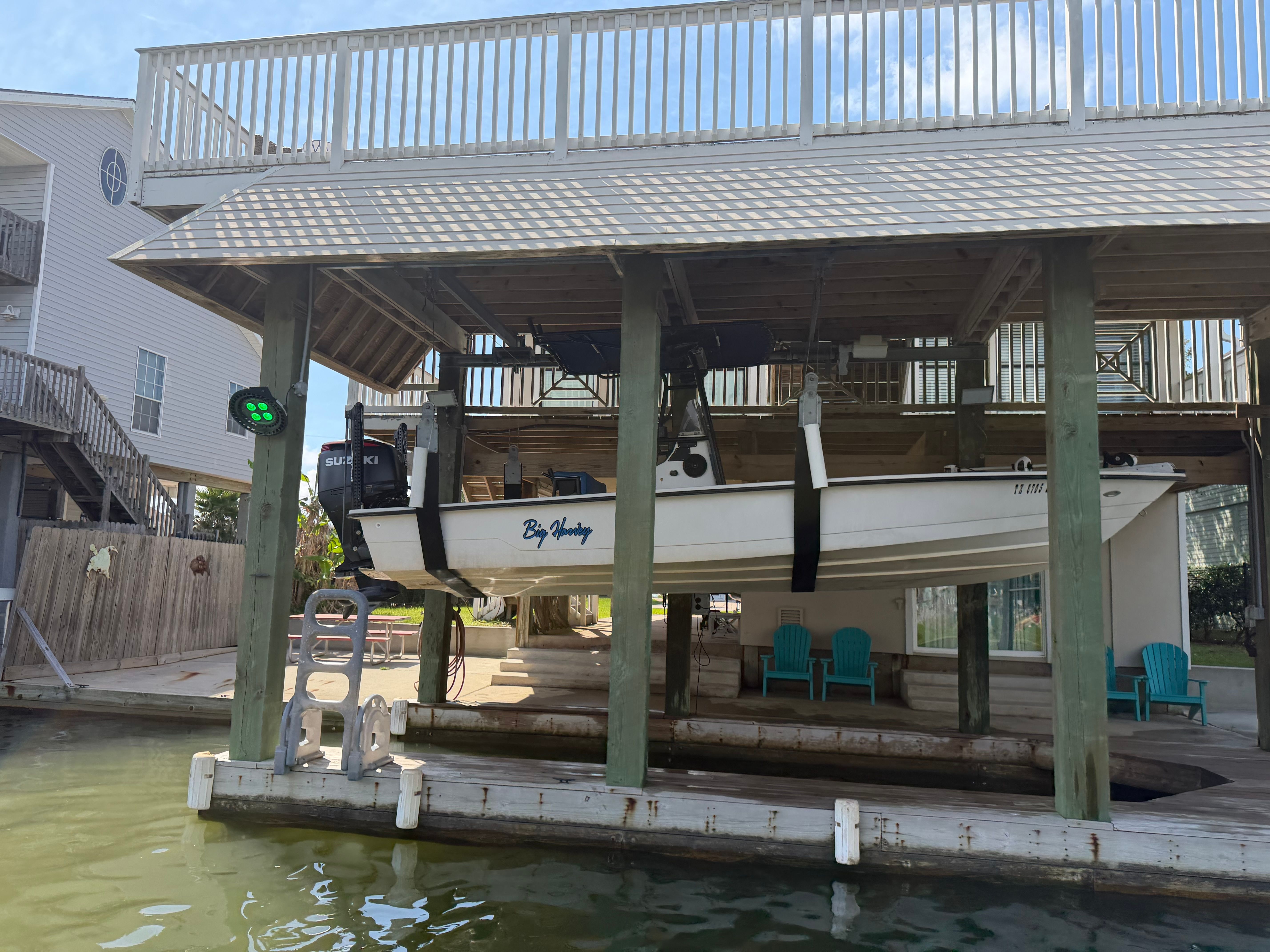 A white boat is suspended in a covered boathouse above the water.