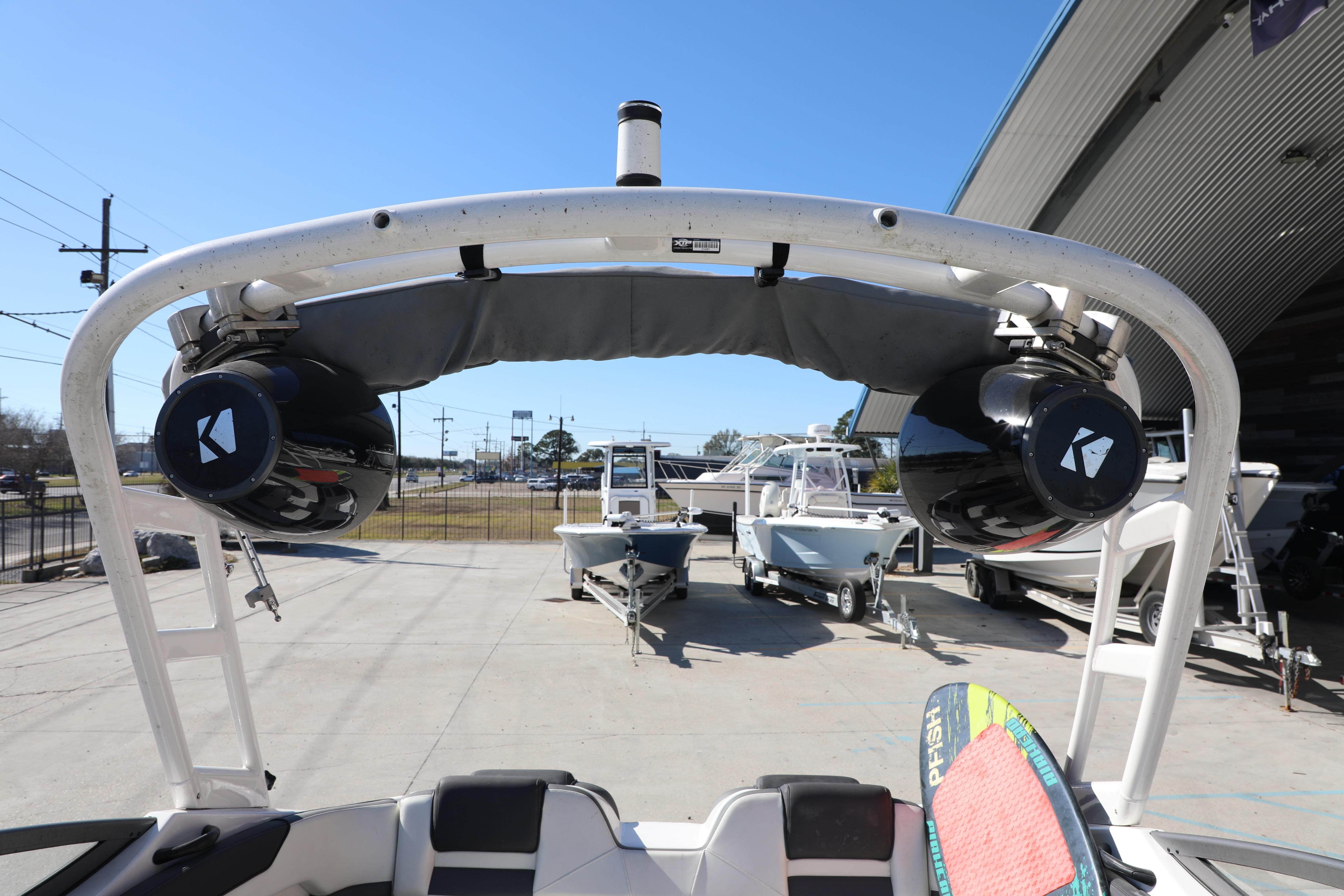 2022 Yamaha AR210 boat with speakers and wakeboard, parked at a marina.