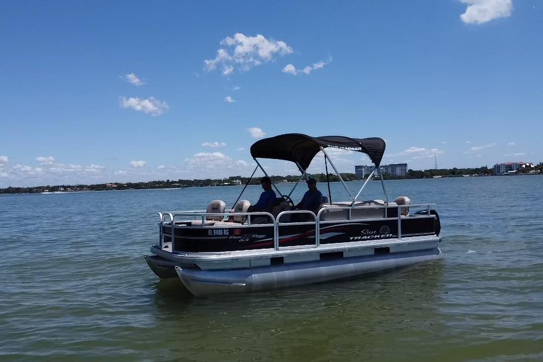 2017 Sun Tracker Bass Buggy 18 DLX pontoon boat cruising on a sunny lake.