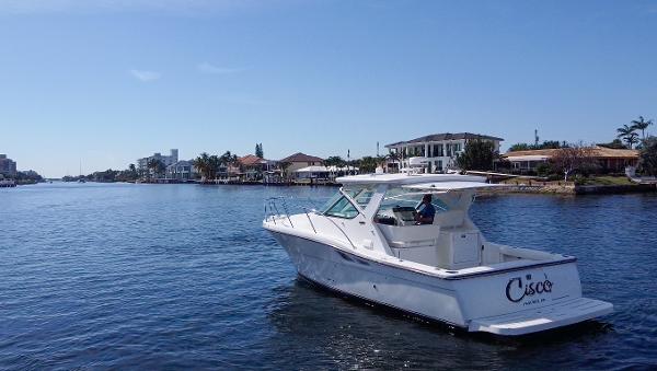 2006 Tiara Yachts 3200 Open cruising on a sunny waterfront with houses in the background.