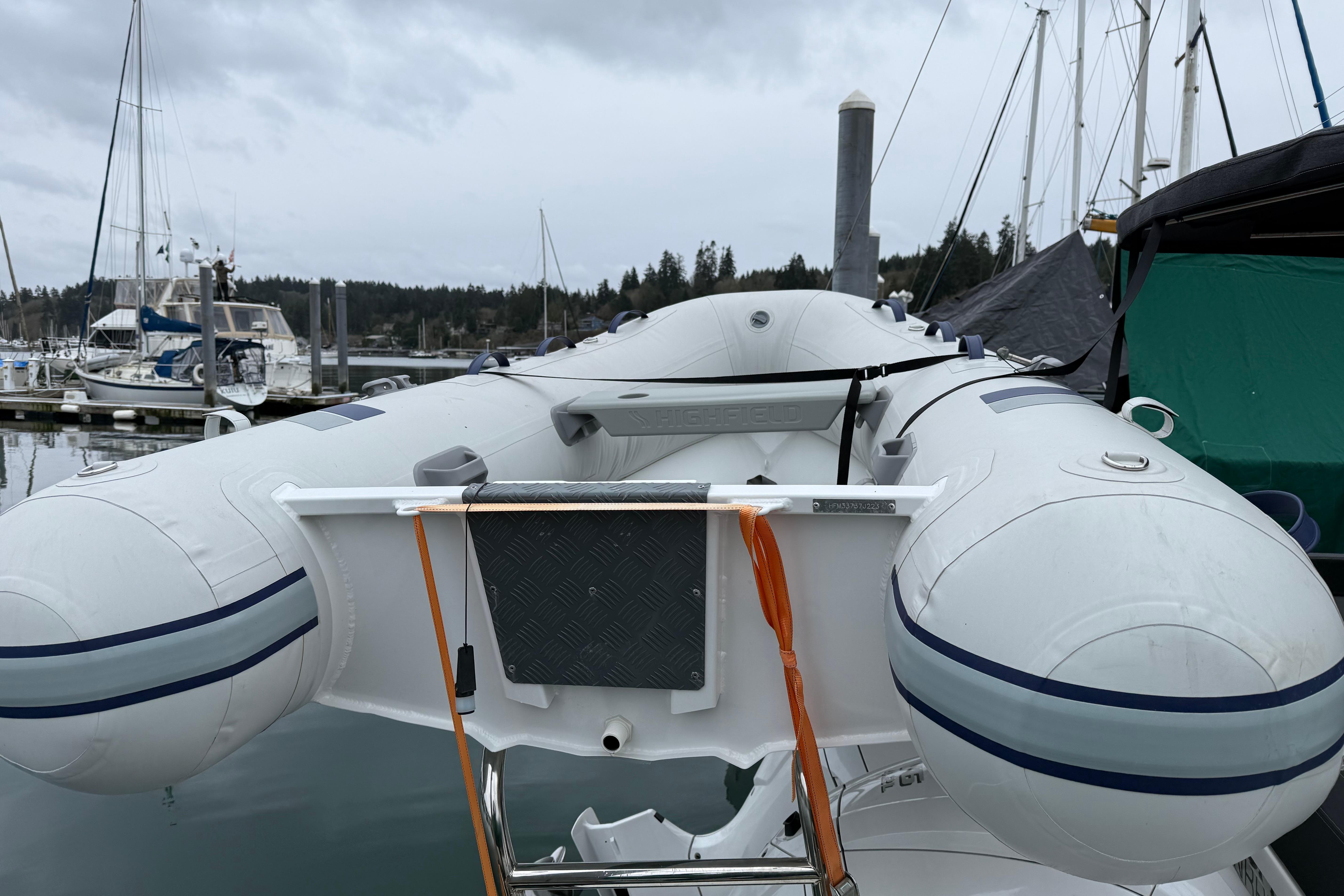 Inflatable boat docked near Jeanneau NC 1095, 2023 model, in a marina setting.