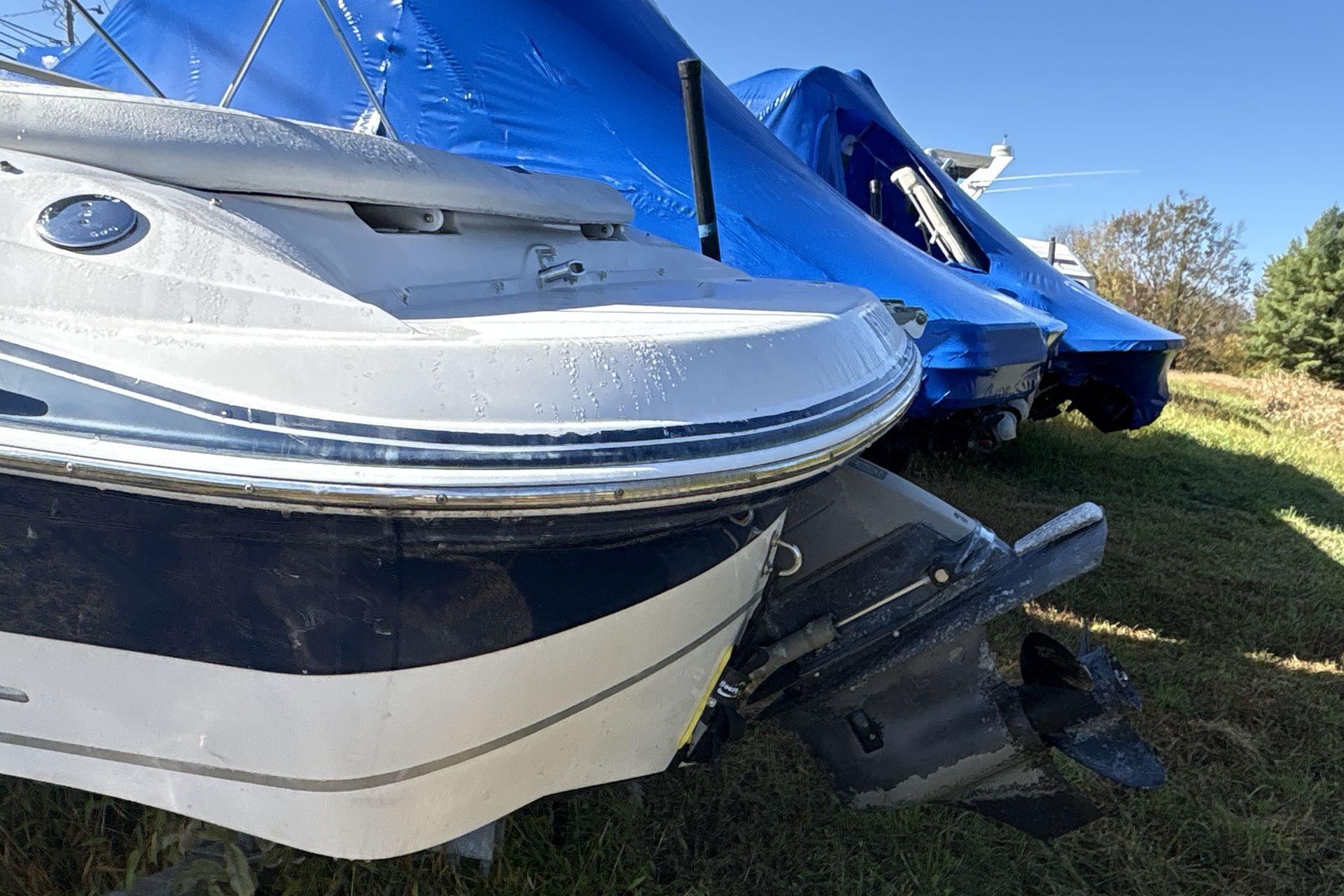 2007 Four Winns 200 Horizon boat, partially covered, on grass with blue tarps in background.