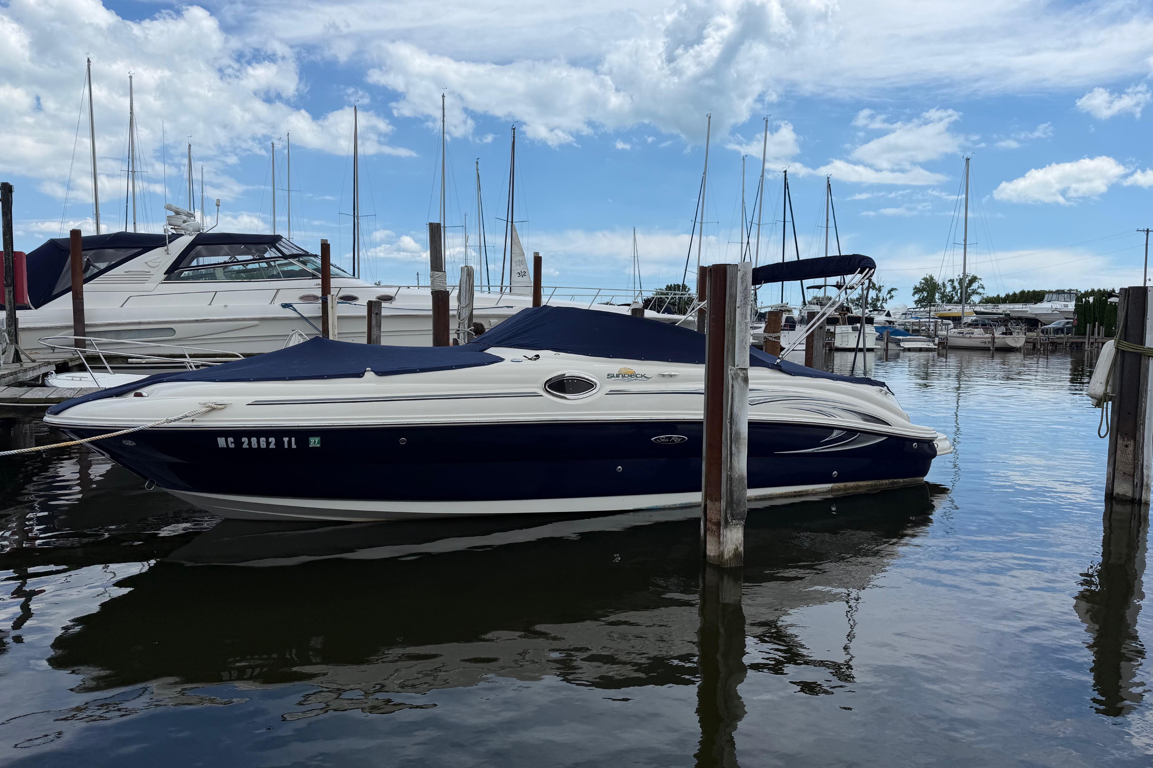 2004 Sea Ray 240 Sundeck boat docked at a marina under a partly cloudy sky.