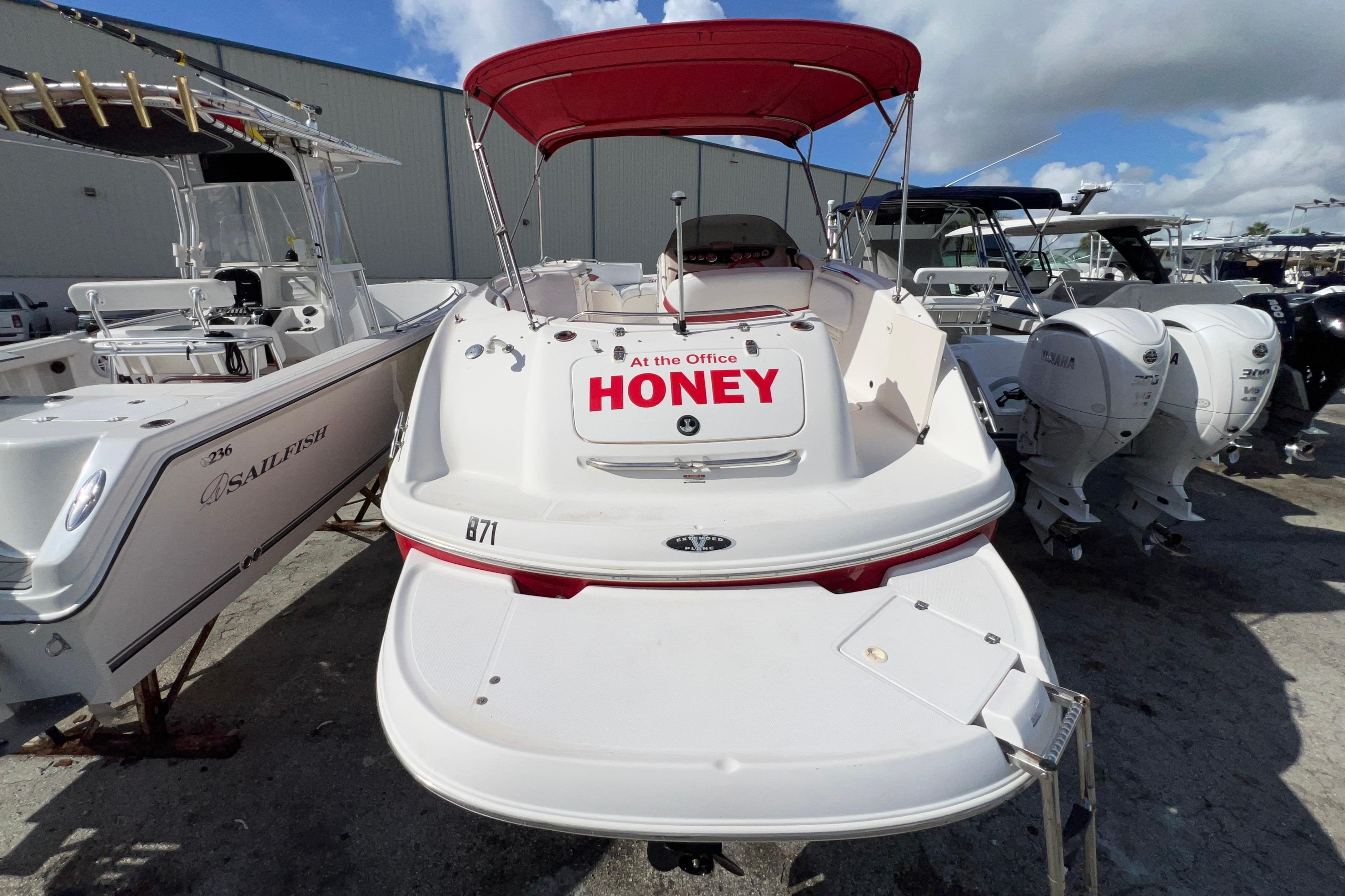 2002 Chaparral 232 Sunesta boat with red canopy, docked alongside other boats.