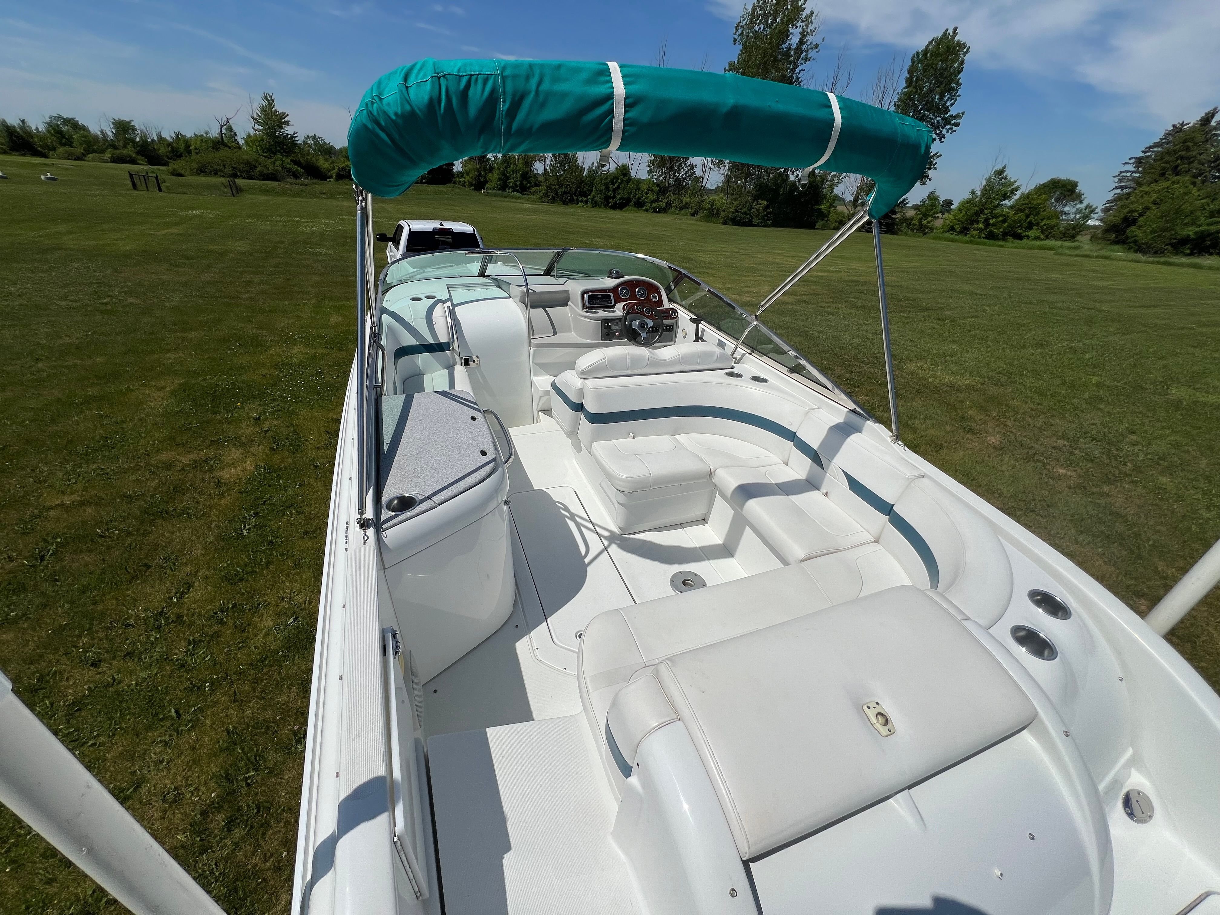 A 2005 Formula 260 Sun Sport boat with white and teal interior, parked on a grassy field.