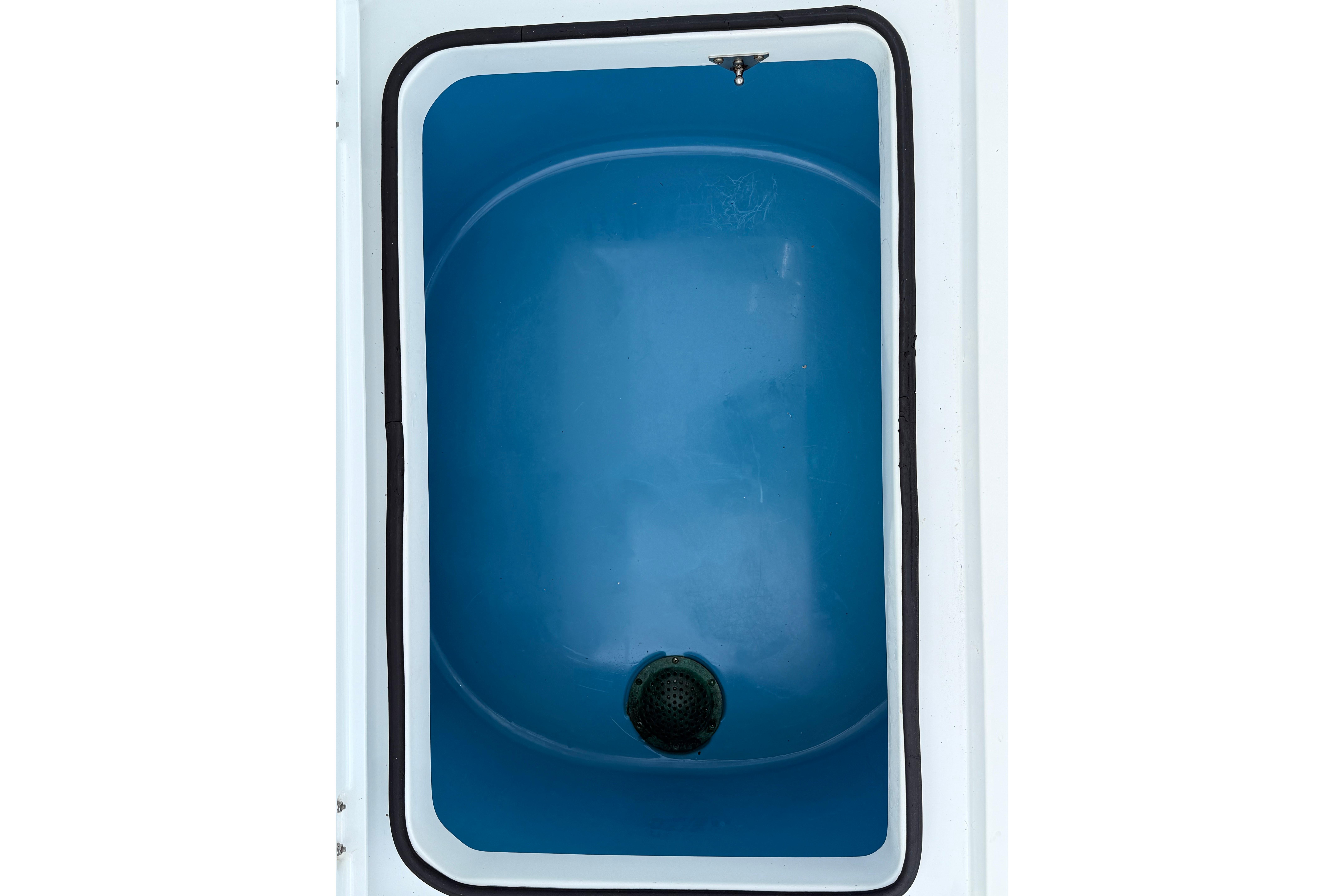 Freeman 34VH 2022 boat livewell with blue interior and drain plug.