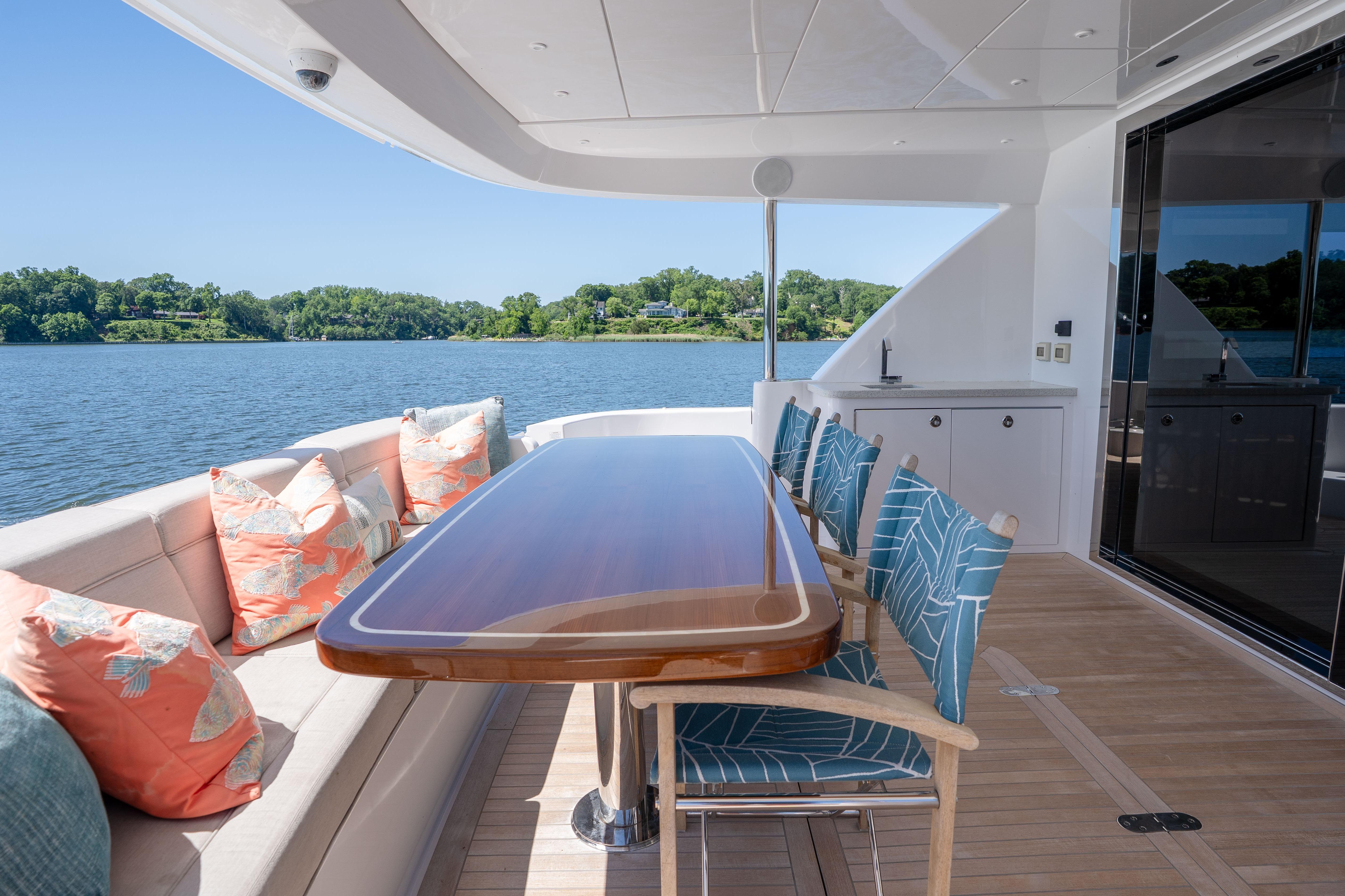Luxurious 2021 Hatteras M75 Panacera yacht deck with elegant dining area and scenic water view.