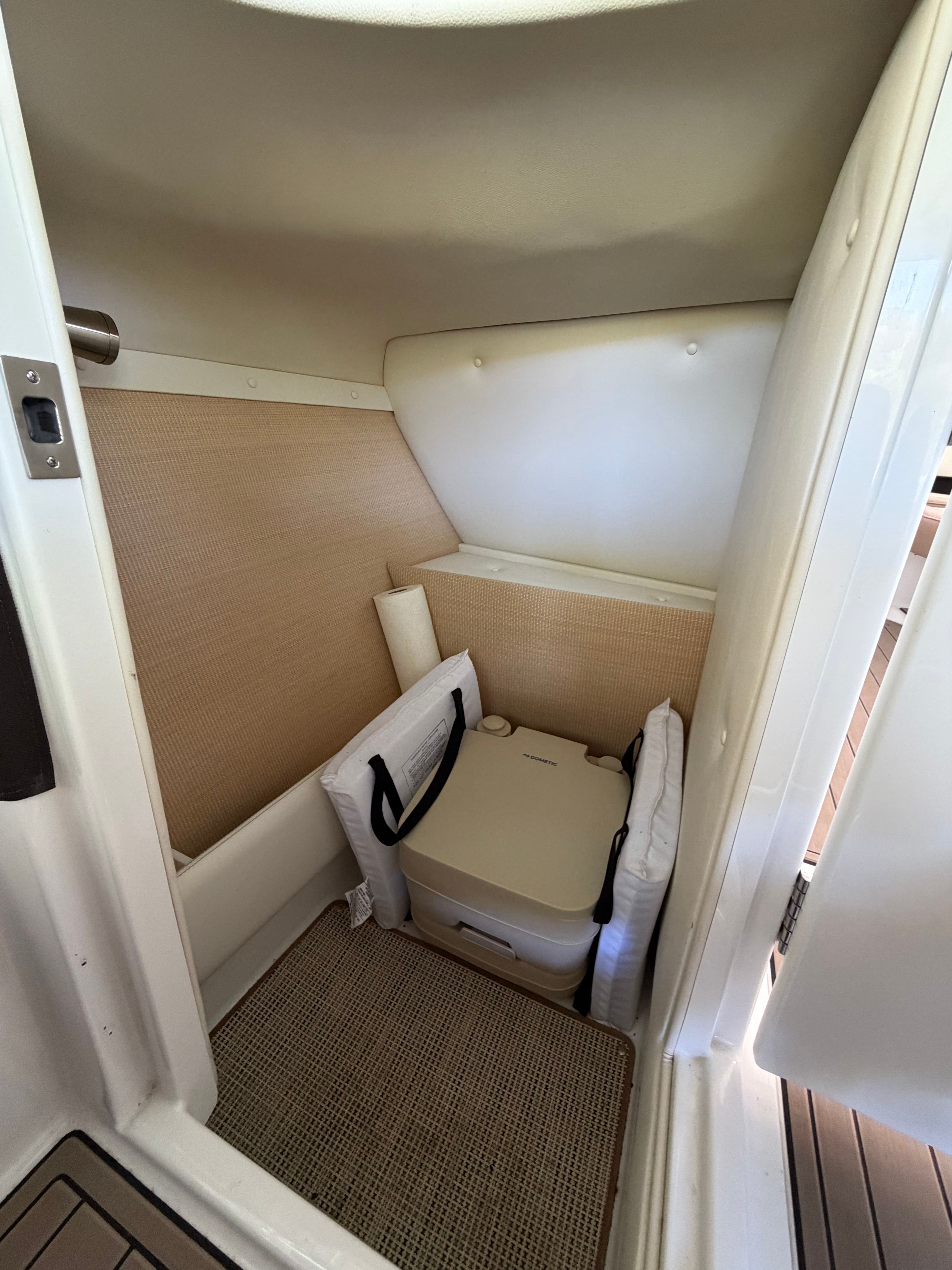 Small interior space of a Cobalt yacht with a portable toilet and cushions.
