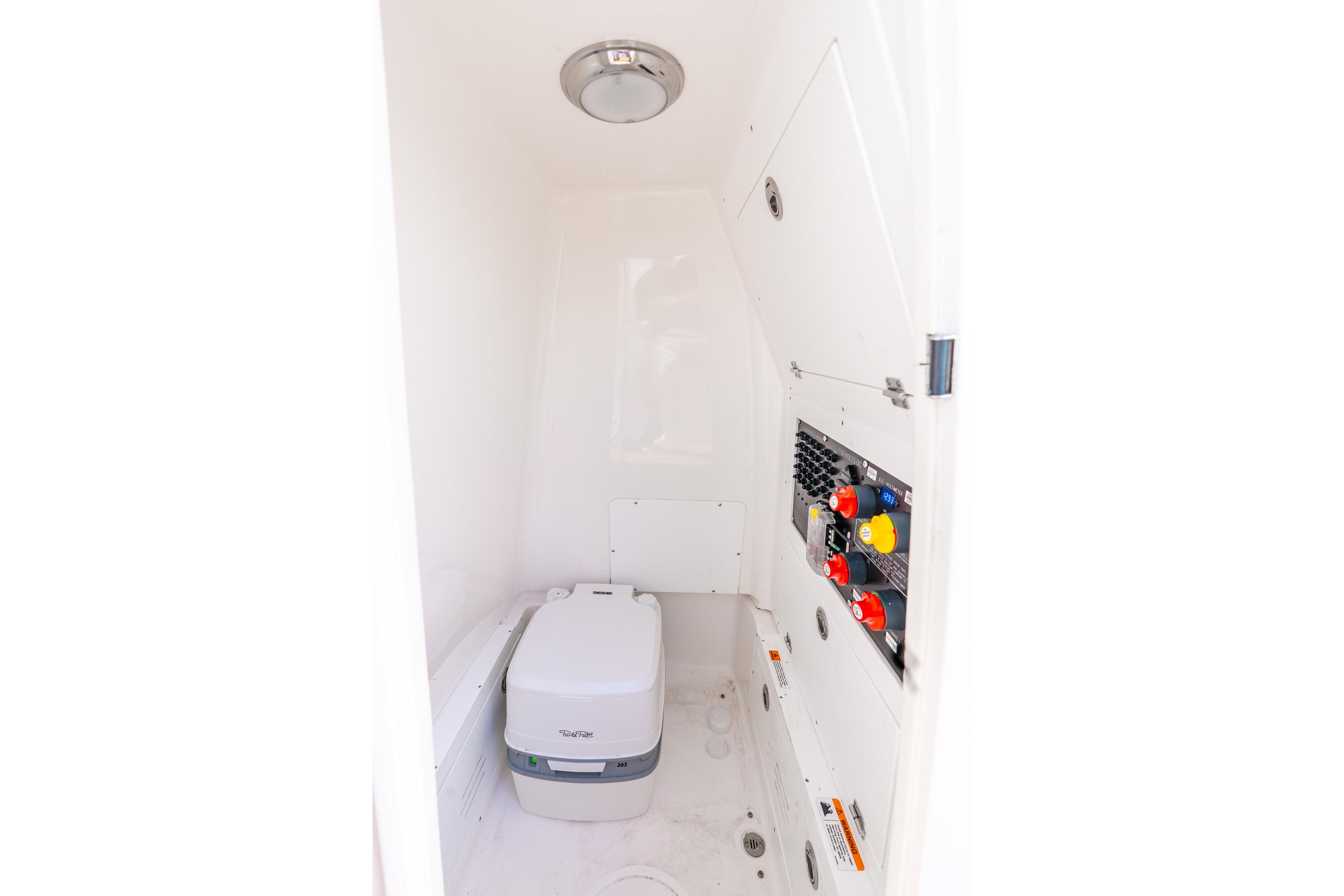2024 Caymas 281 HB boat interior with compact toilet and control panel.