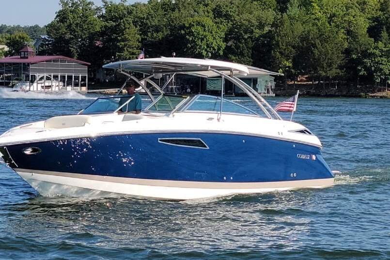 2022 Cobalt R35 boat cruising on a lake with lush green trees in the background.