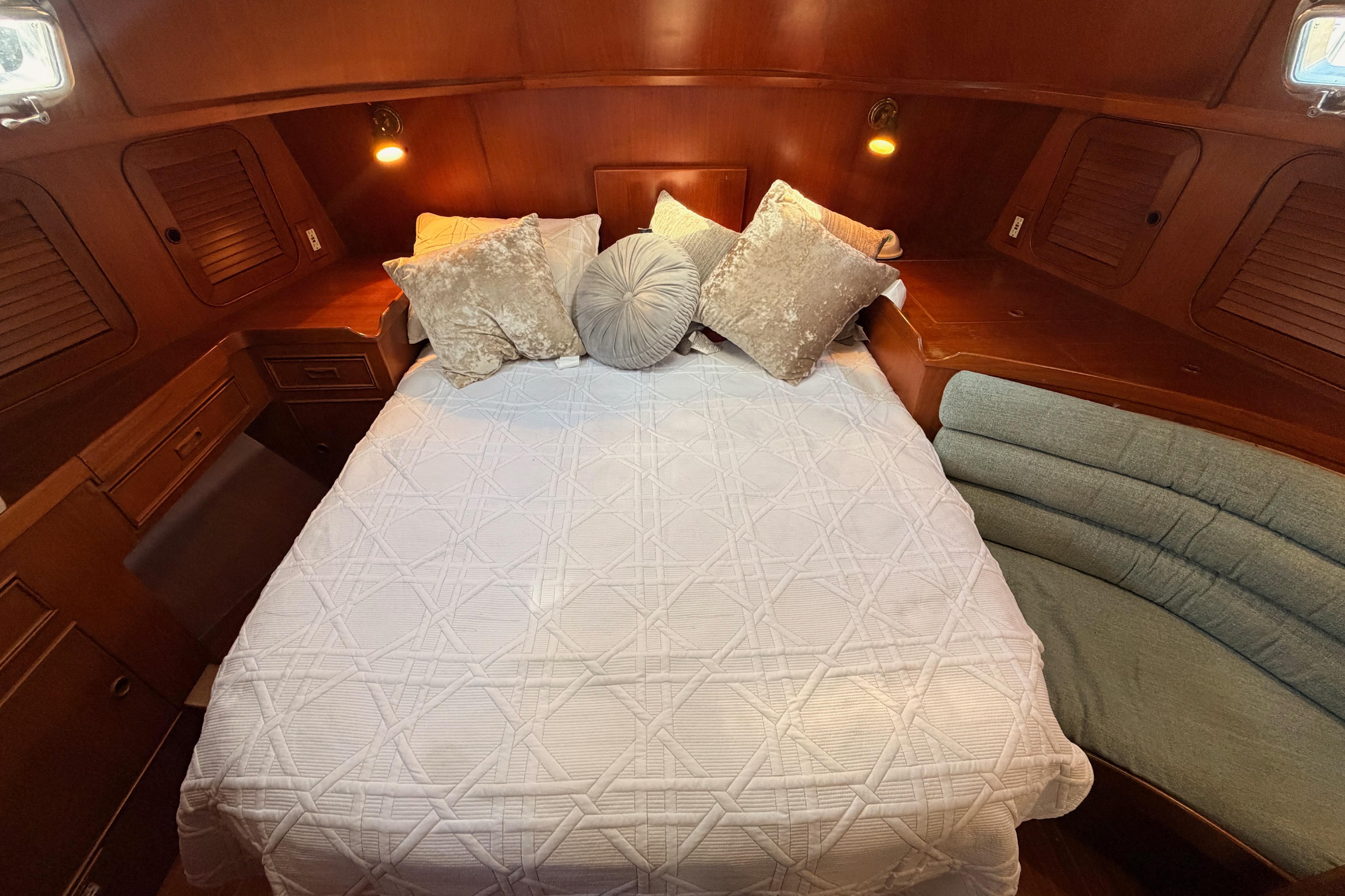 Cozy cabin interior of a 1991 Hylas 51 yacht with elegant bedding and warm lighting.
