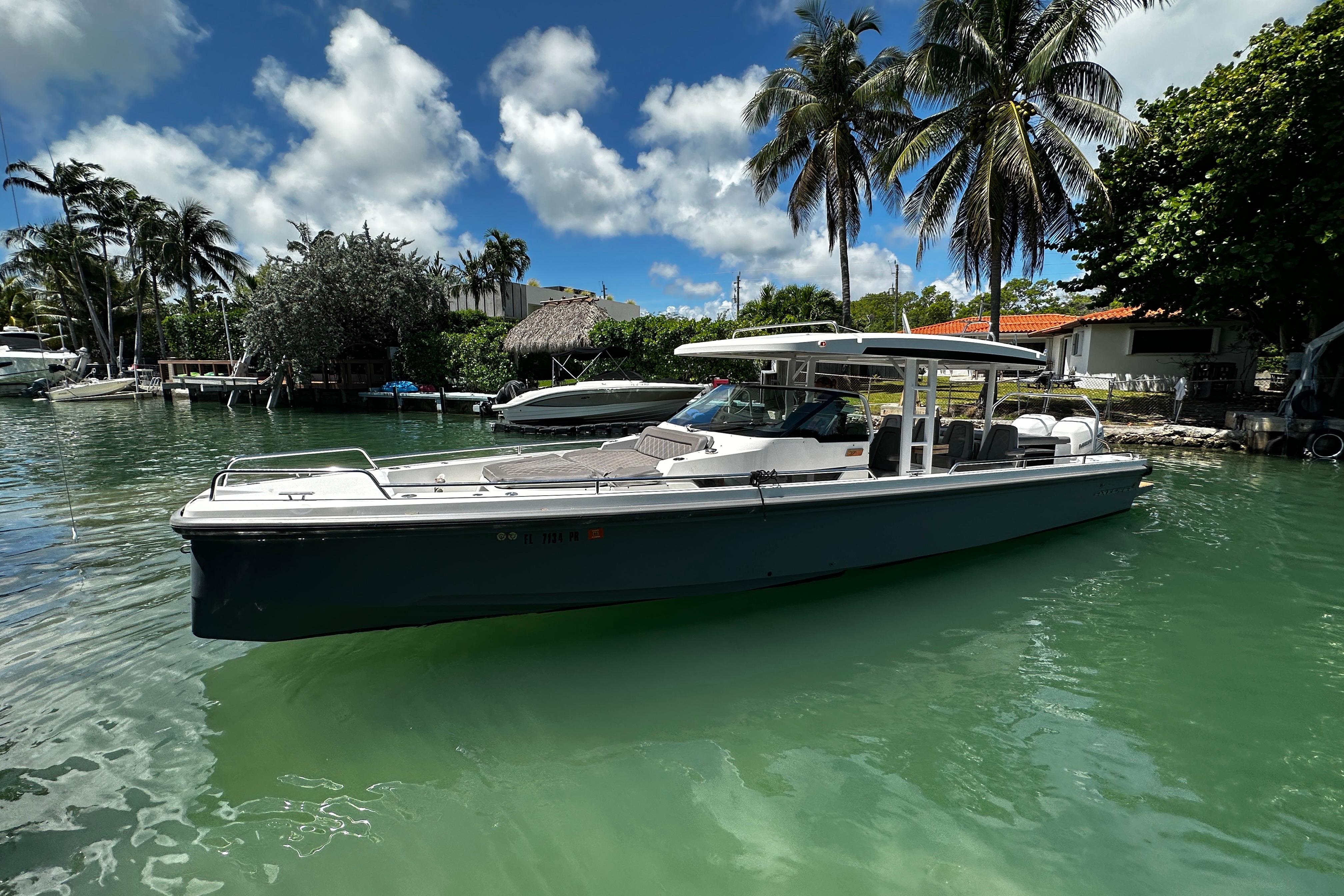 2018 Axopar 37 Sun-Top boat on tropical water, surrounded by palm trees.