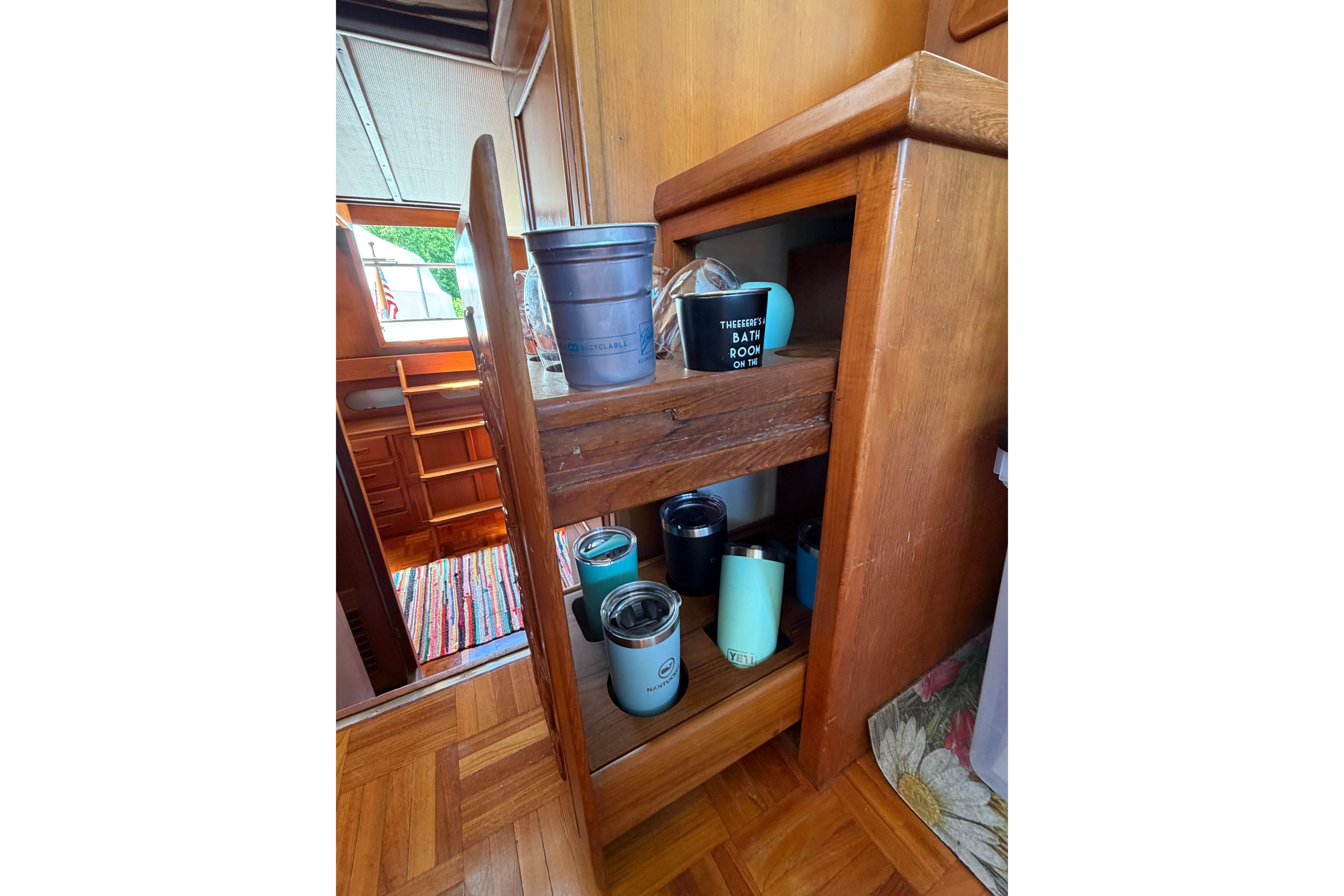 Wooden interior shelves on a 1987 Marine Trader 36 boat, holding various mugs and containers.