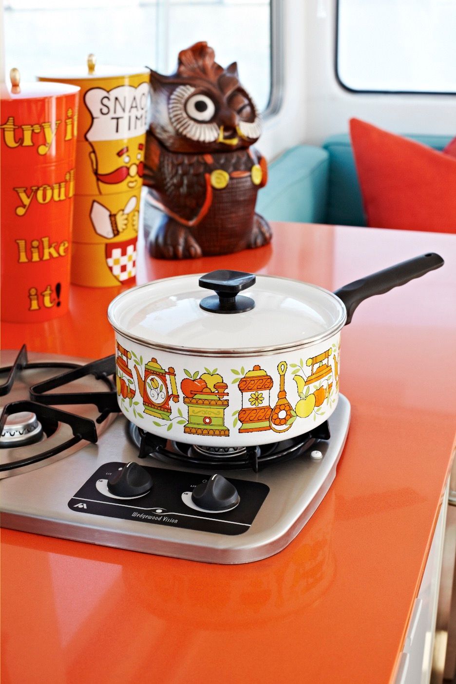 A colorful pot sits on a stove in a cozy houseboat.
