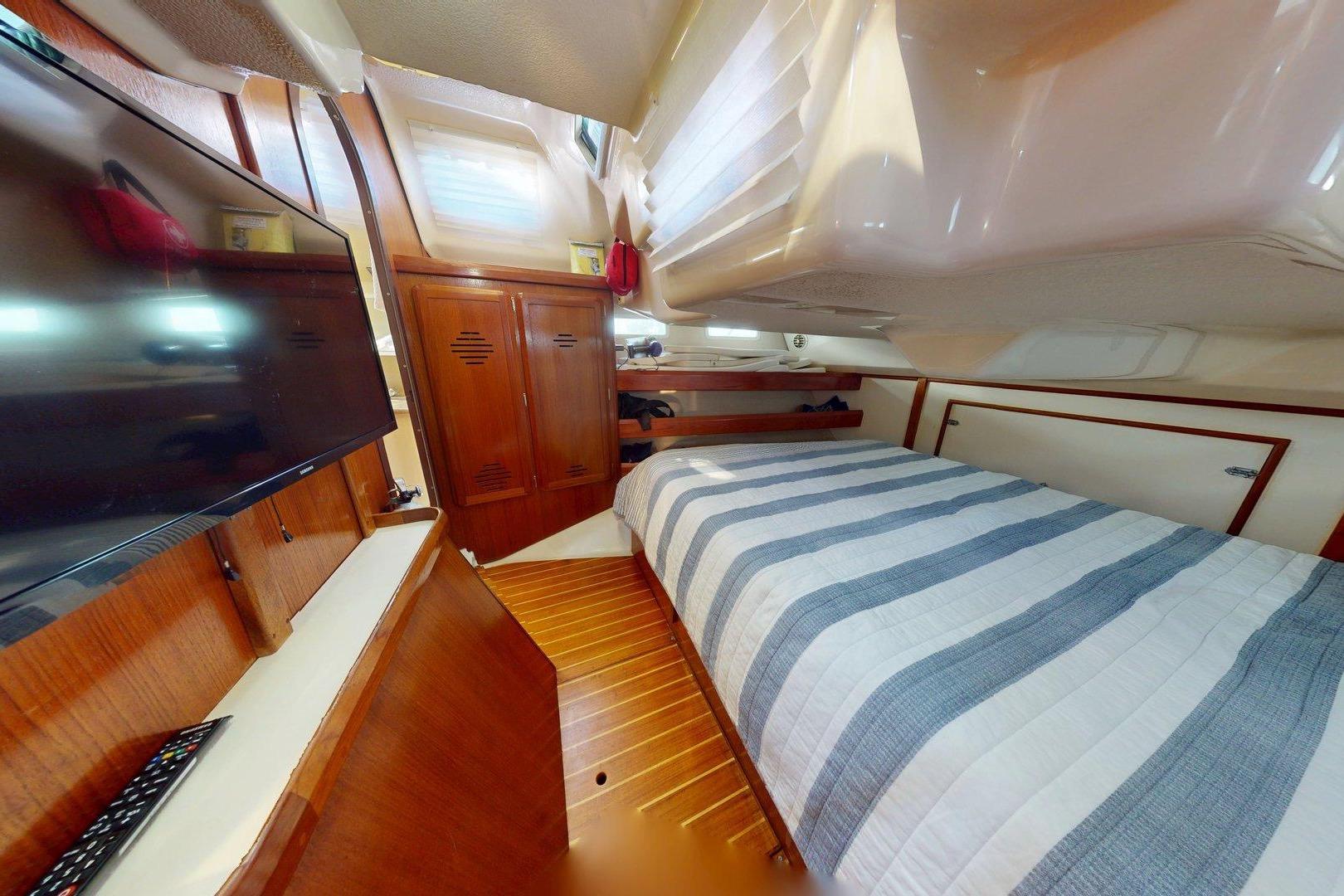 Interior of 1997 Hunter Legend 40.5 yacht with cozy cabin and striped bedding.