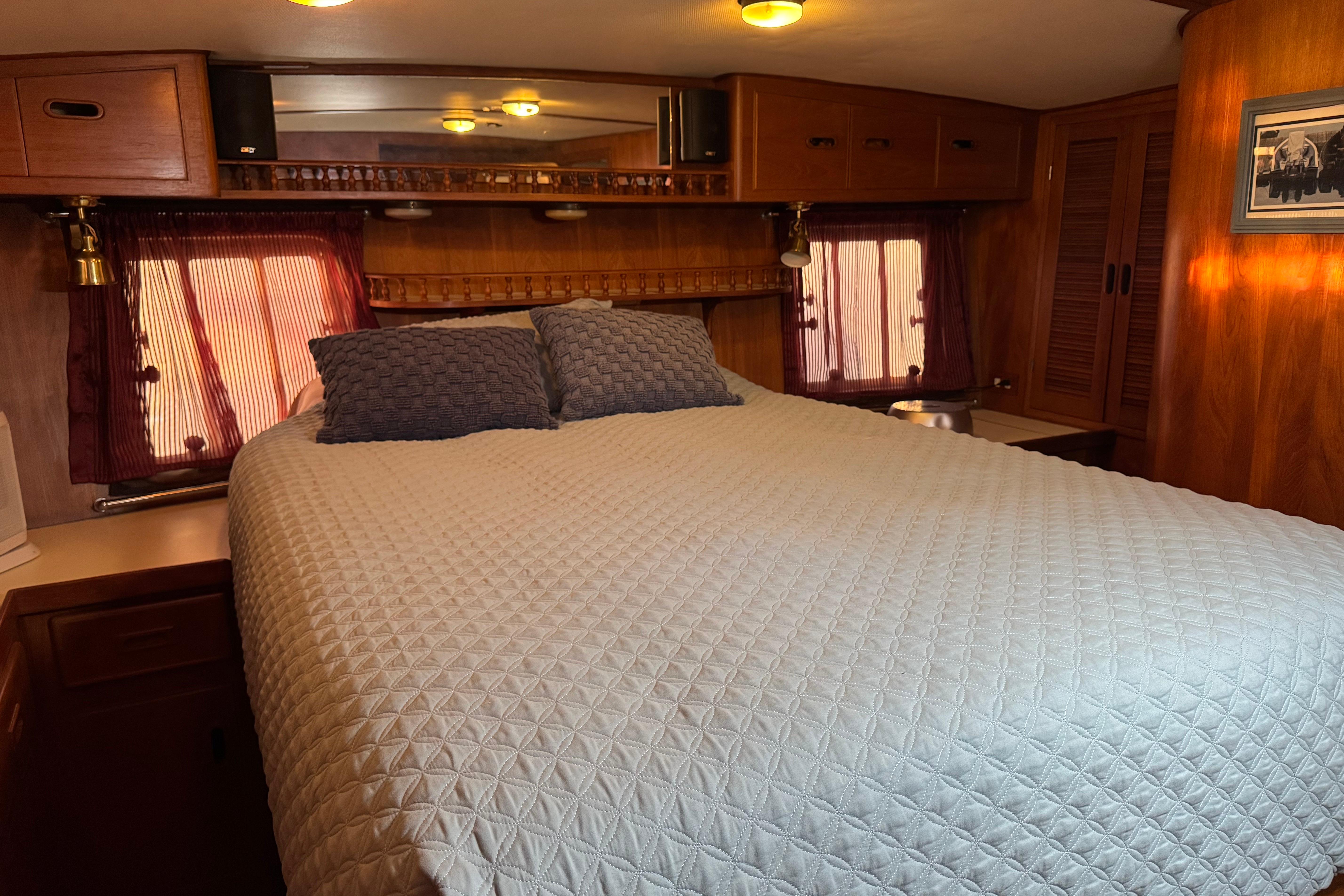 Cozy bedroom in a 1987 President 37 RV with quilted bedding and wooden cabinetry.