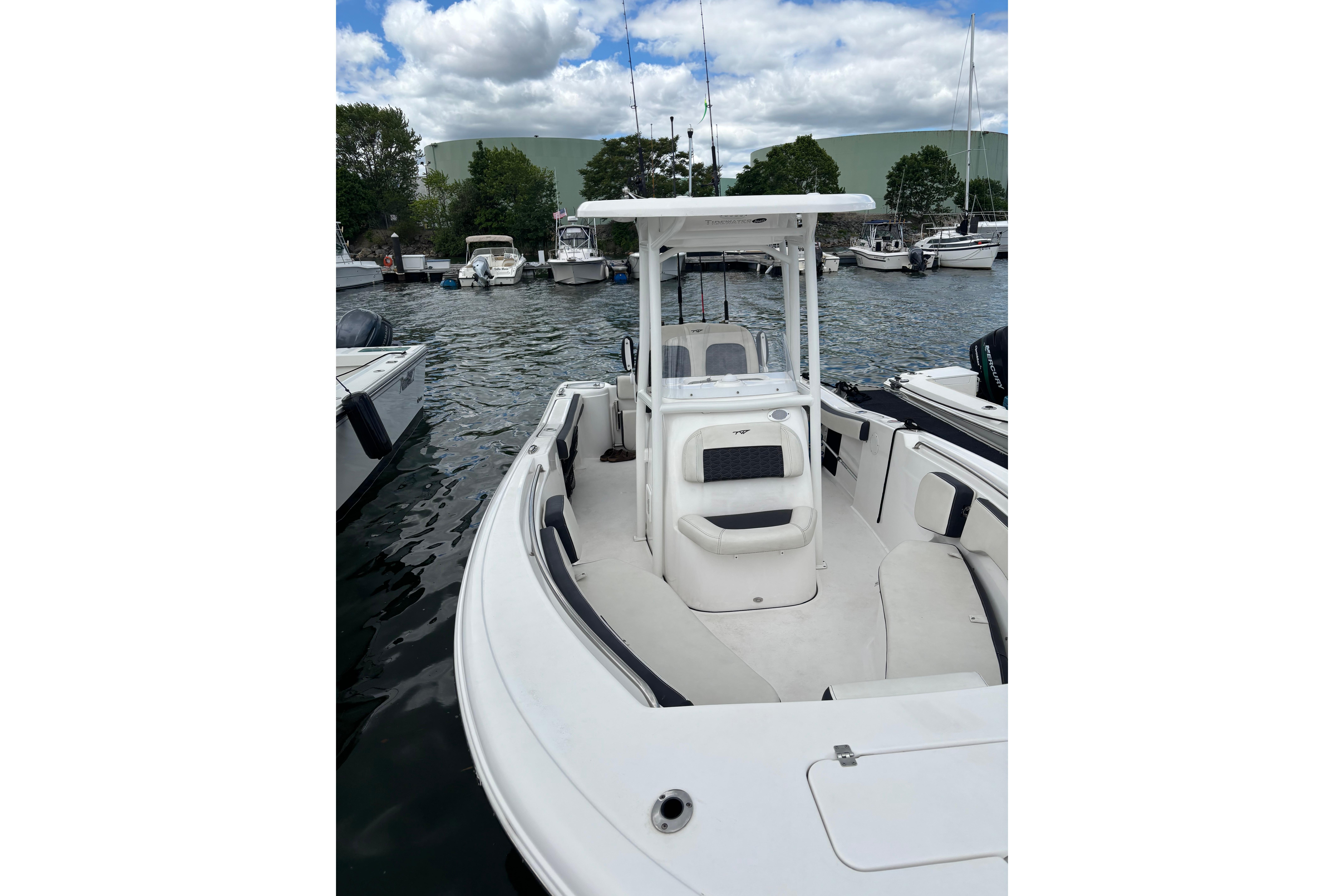 2024 Tidewater 220 CC Adventure boat docked in a marina under a cloudy sky.