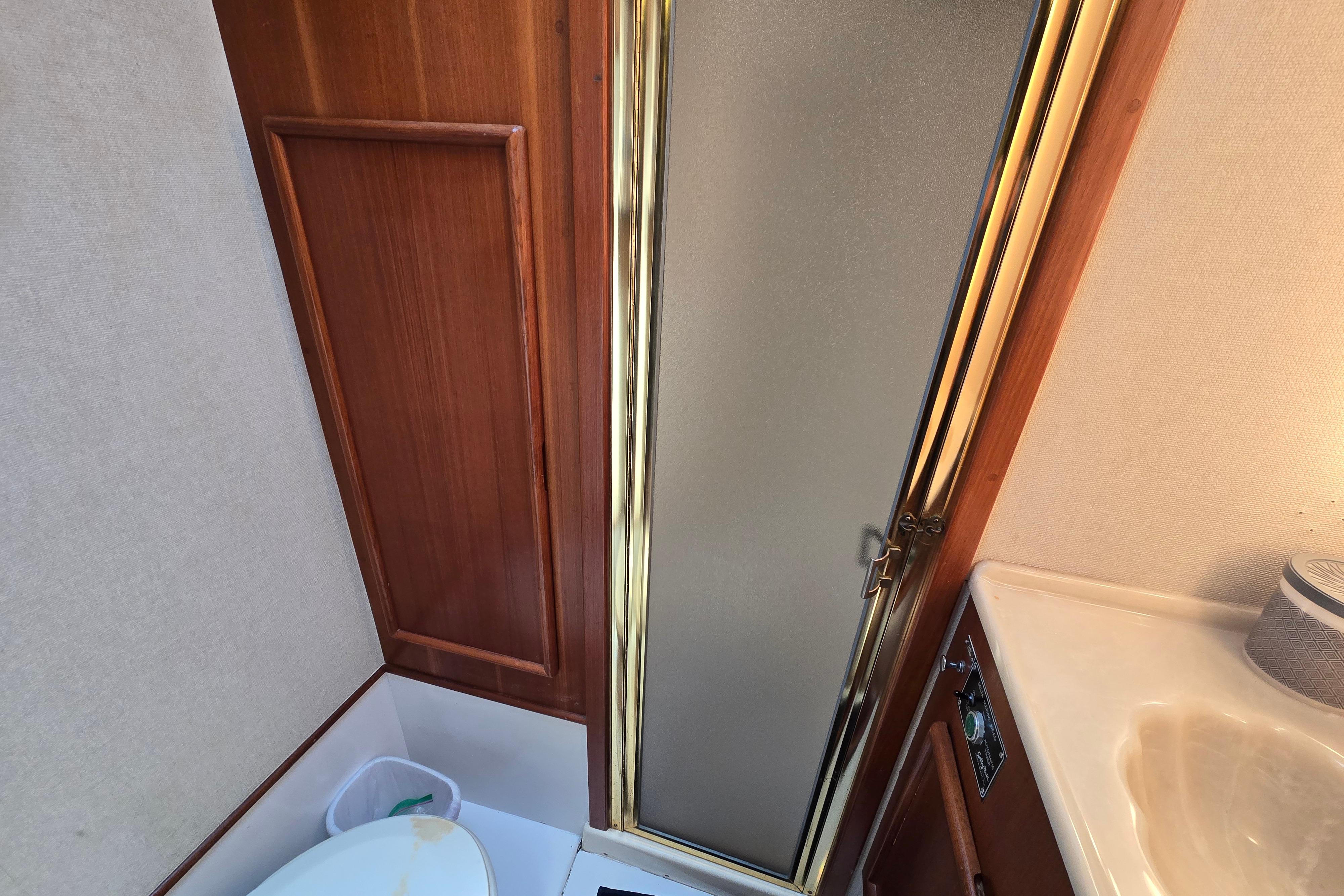 Bathroom interior of 1988 Post 46 Convertible yacht with wooden paneling and shower.