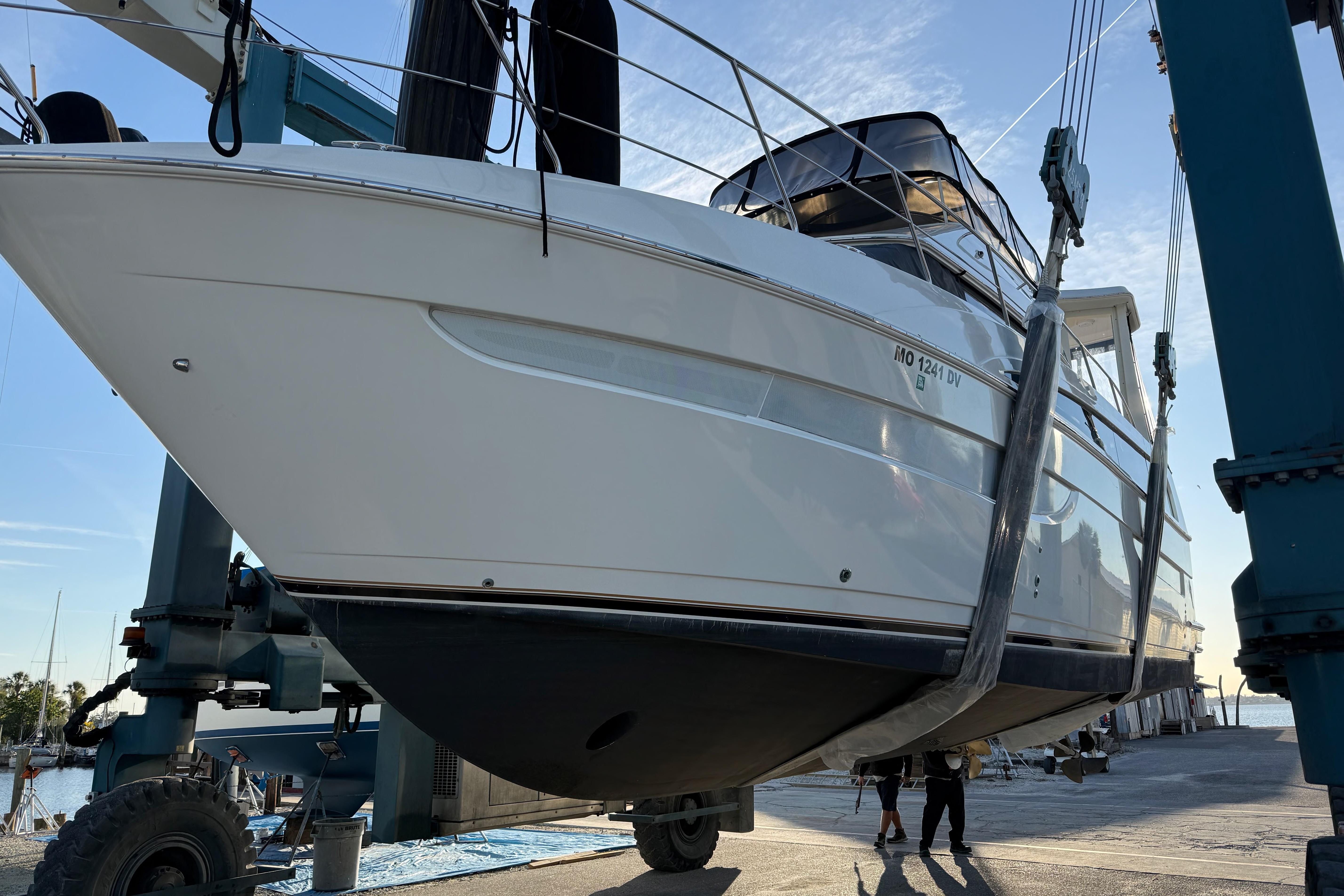 2006 Carver 43 Motor Yacht being lifted at a marina under clear skies.