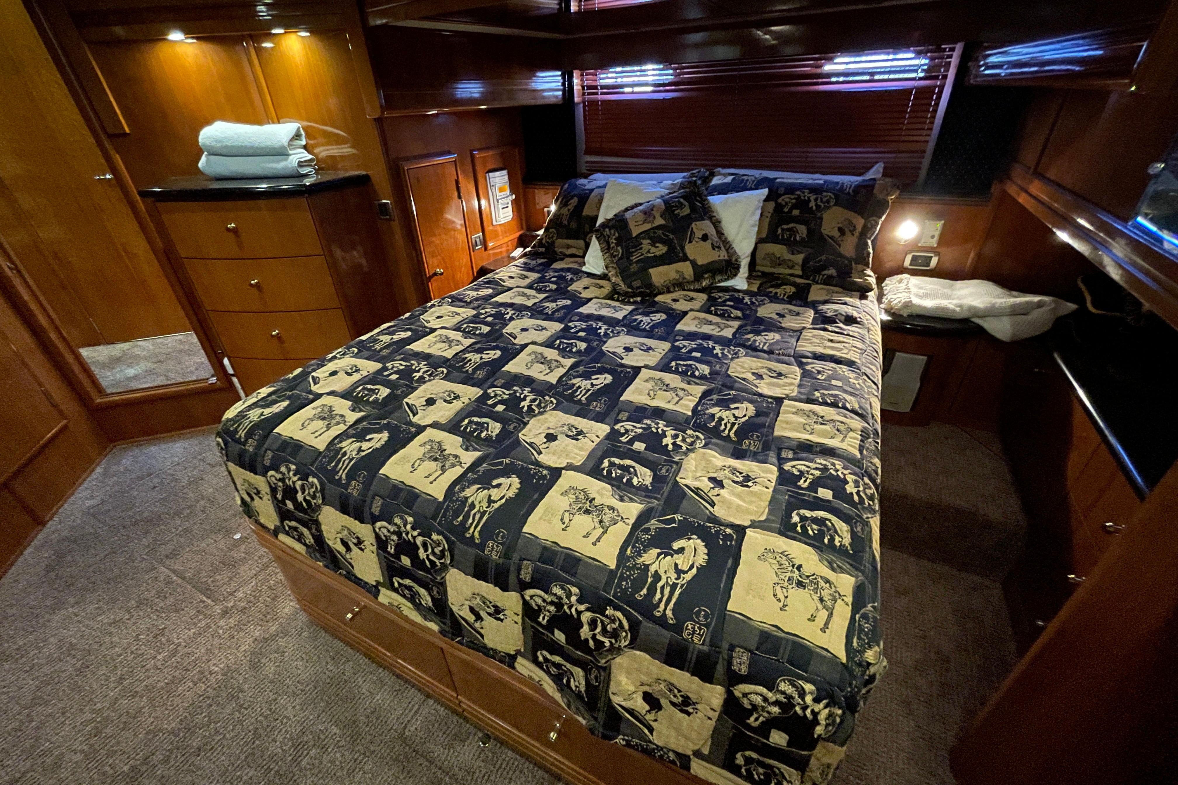 Luxurious bedroom interior of 2002 Carver 570 Voyager Pilothouse yacht with patterned bedding.