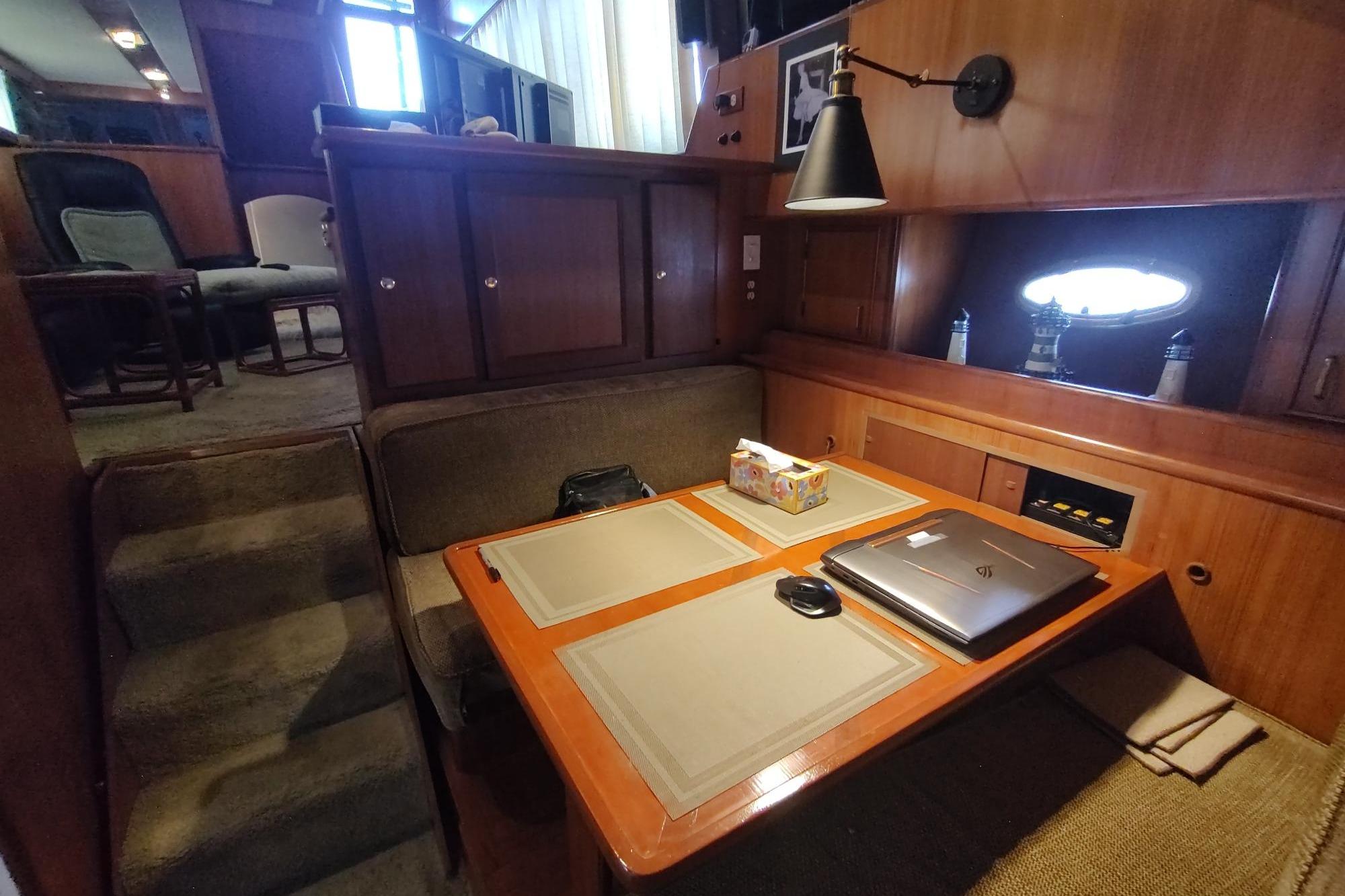 Interior of 1989 Hyatt Double Cabin Motoryacht with dining area and laptop on table.