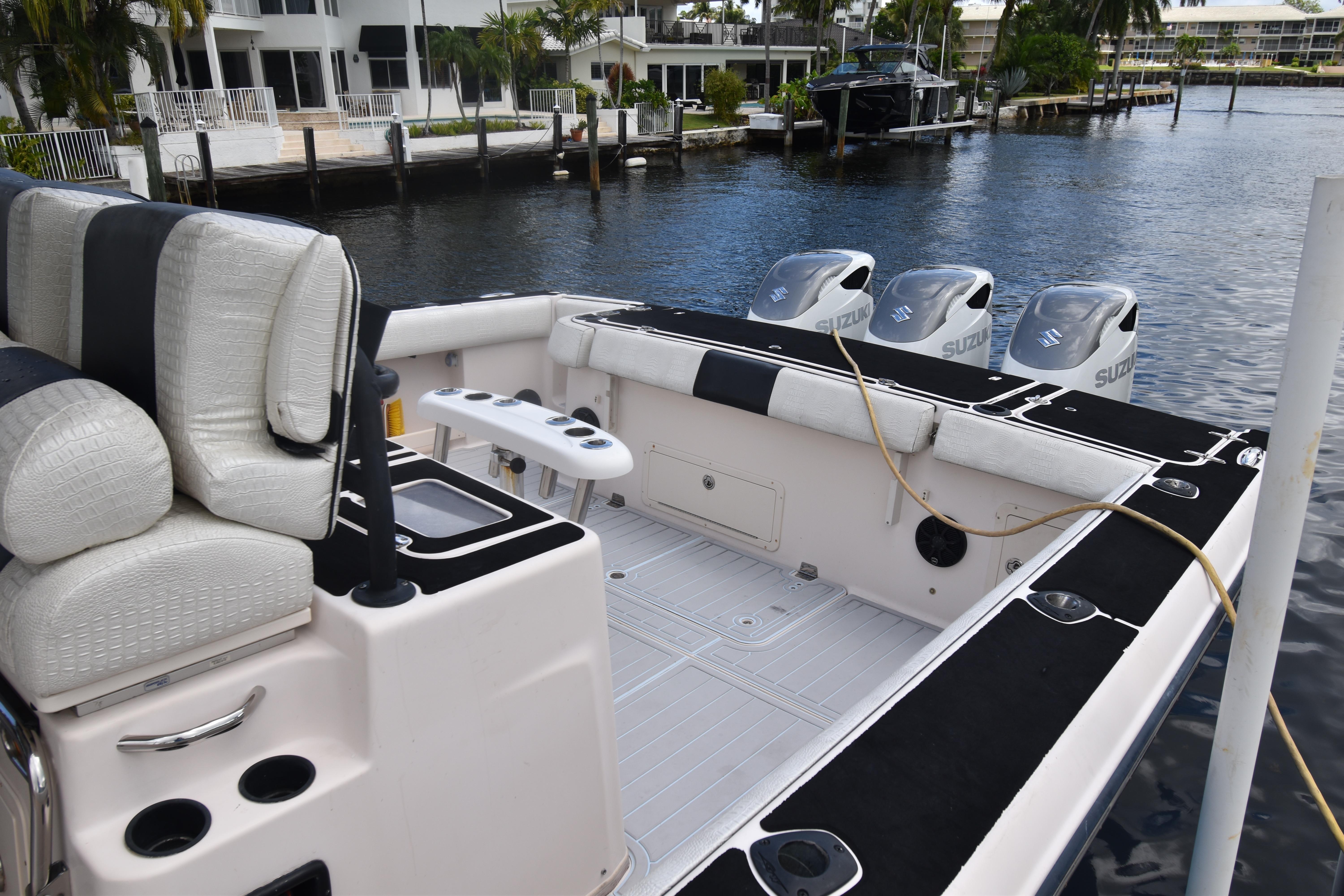 2010 Grady-White Canyon 366 boat with triple Suzuki engines docked by waterfront homes.