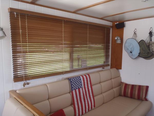 Interior of 2025 Great Harbour N40 with beige sofa, American flag, and wooden blinds.