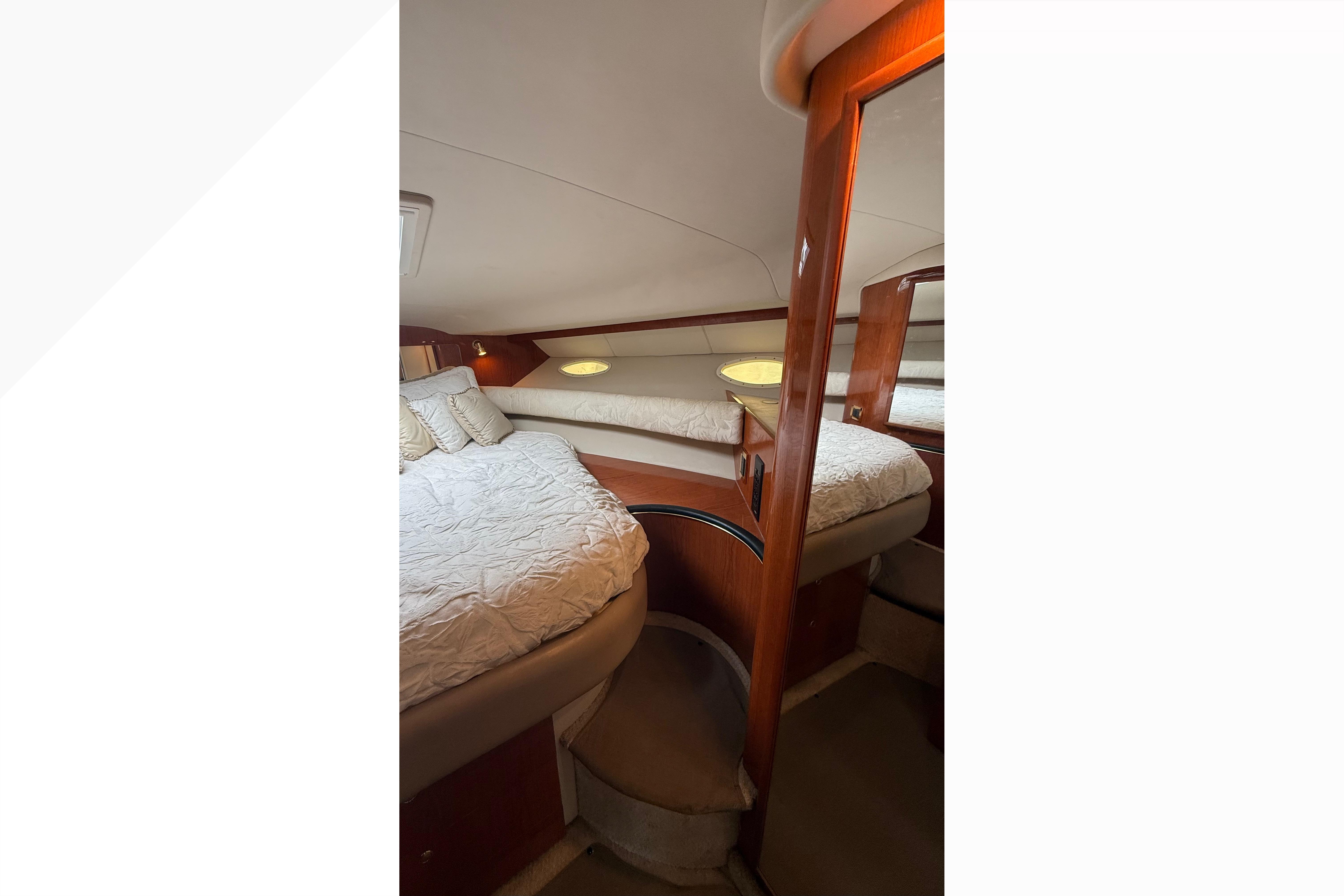 Interior cabin of 1998 Sea Ray Sundancer 400 yacht with cozy bedding and wooden accents.