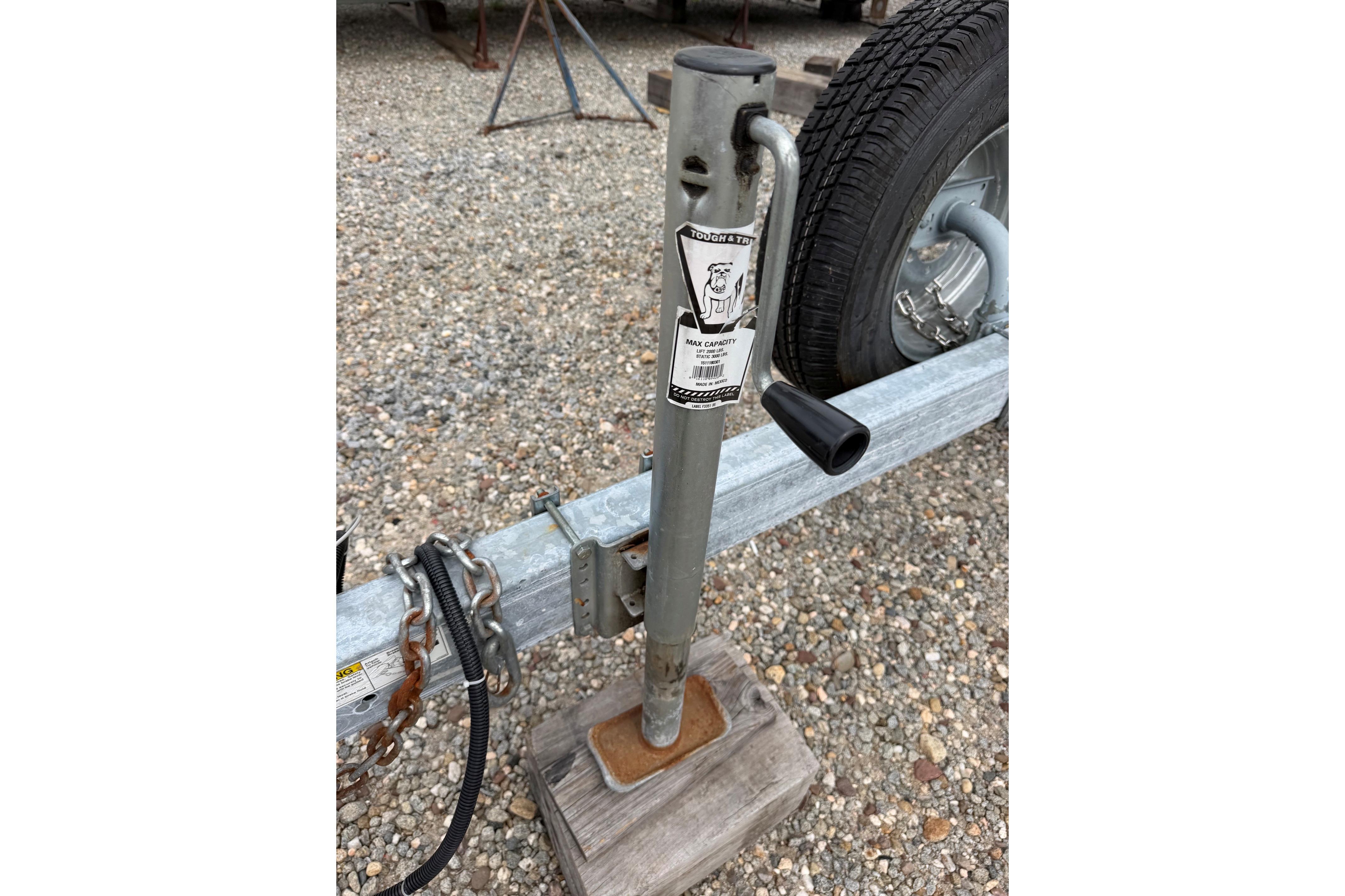 Trailer jack on gravel, supporting a 2000 Sea Ray 240 Sundancer boat trailer.
