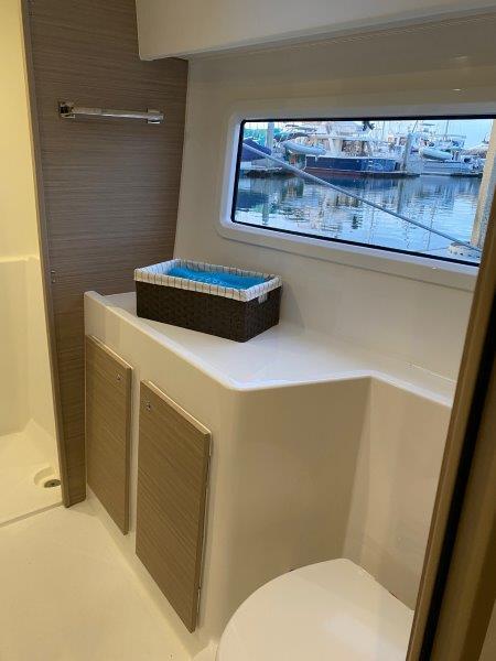 Modern bathroom interior of 2024 Lagoon 42 yacht with marina view.