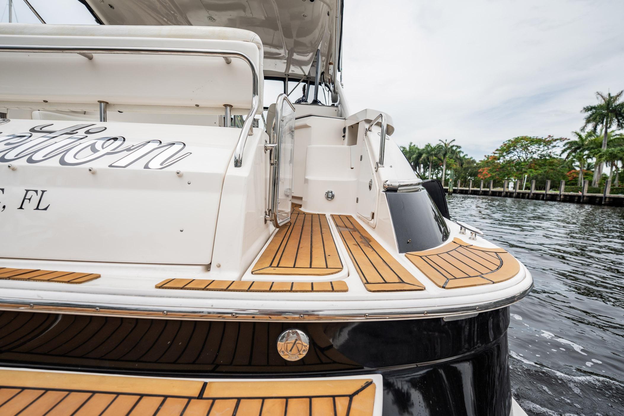 2008 Regal Commodore 4460 yacht with teak deck, docked by palm trees.