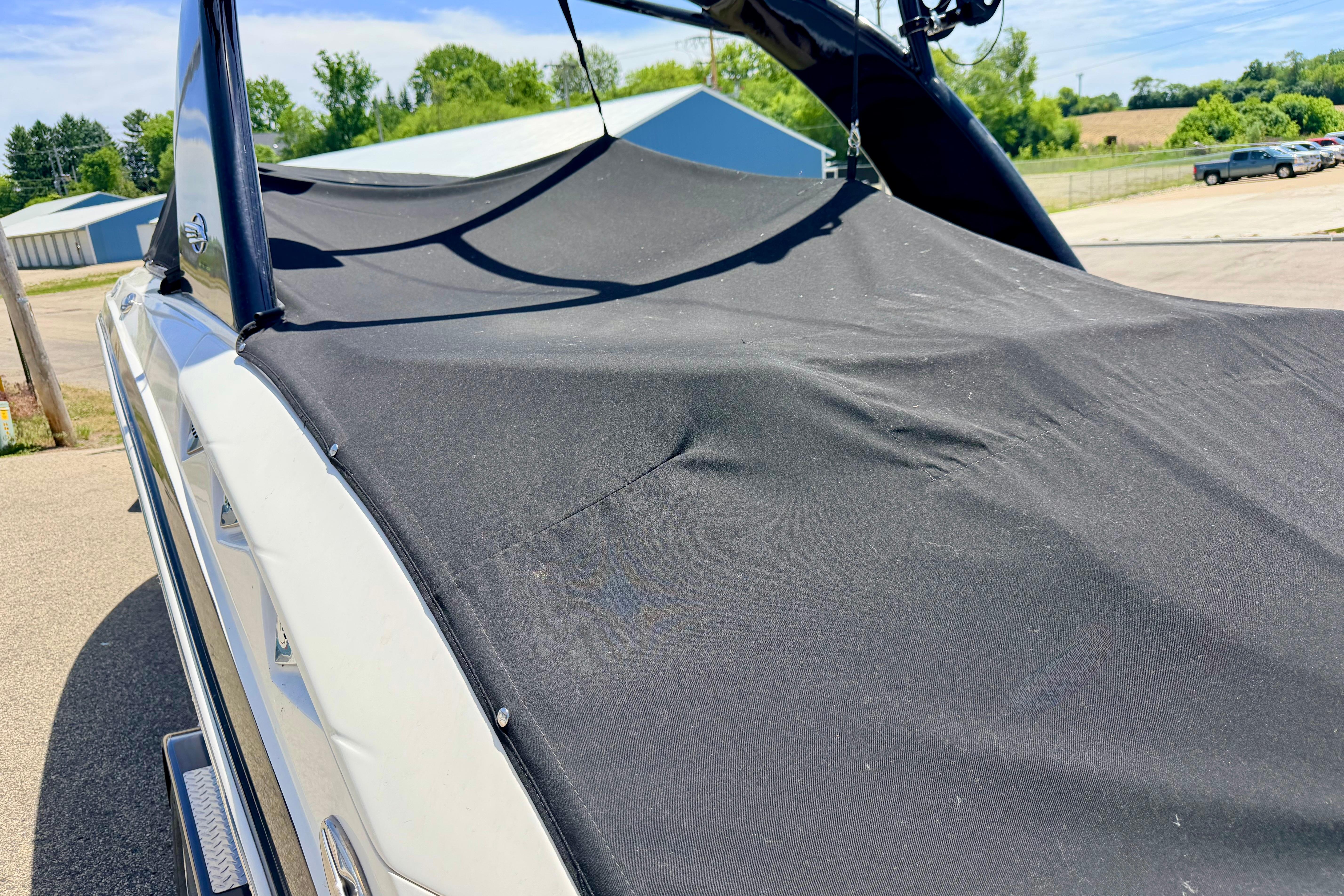 2015 Chaparral Sunesta 264 boat with black cover in outdoor setting.