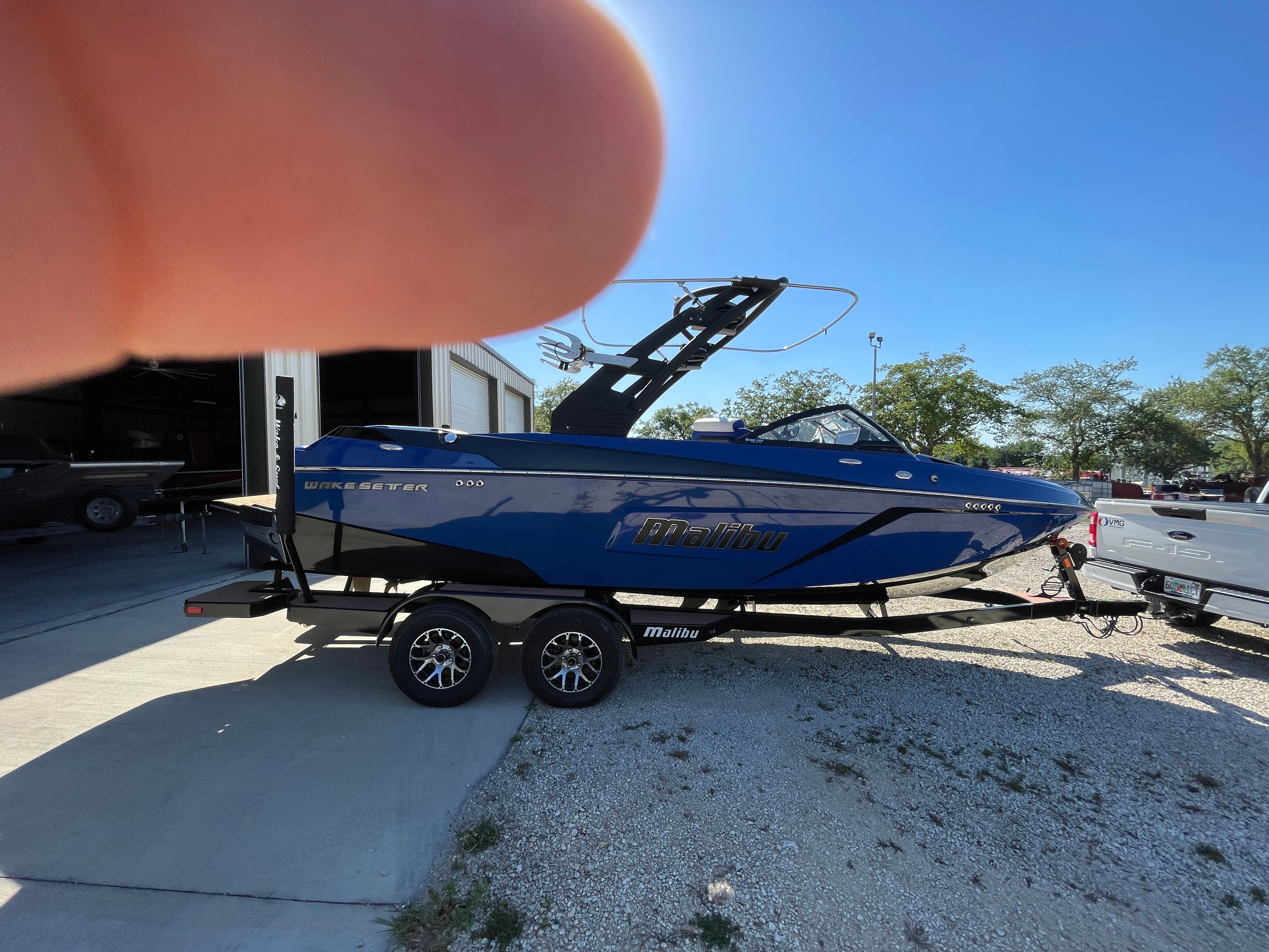 A blue 2019 Malibu Wakesetter 22 LSV sits on a trailer outdoors.