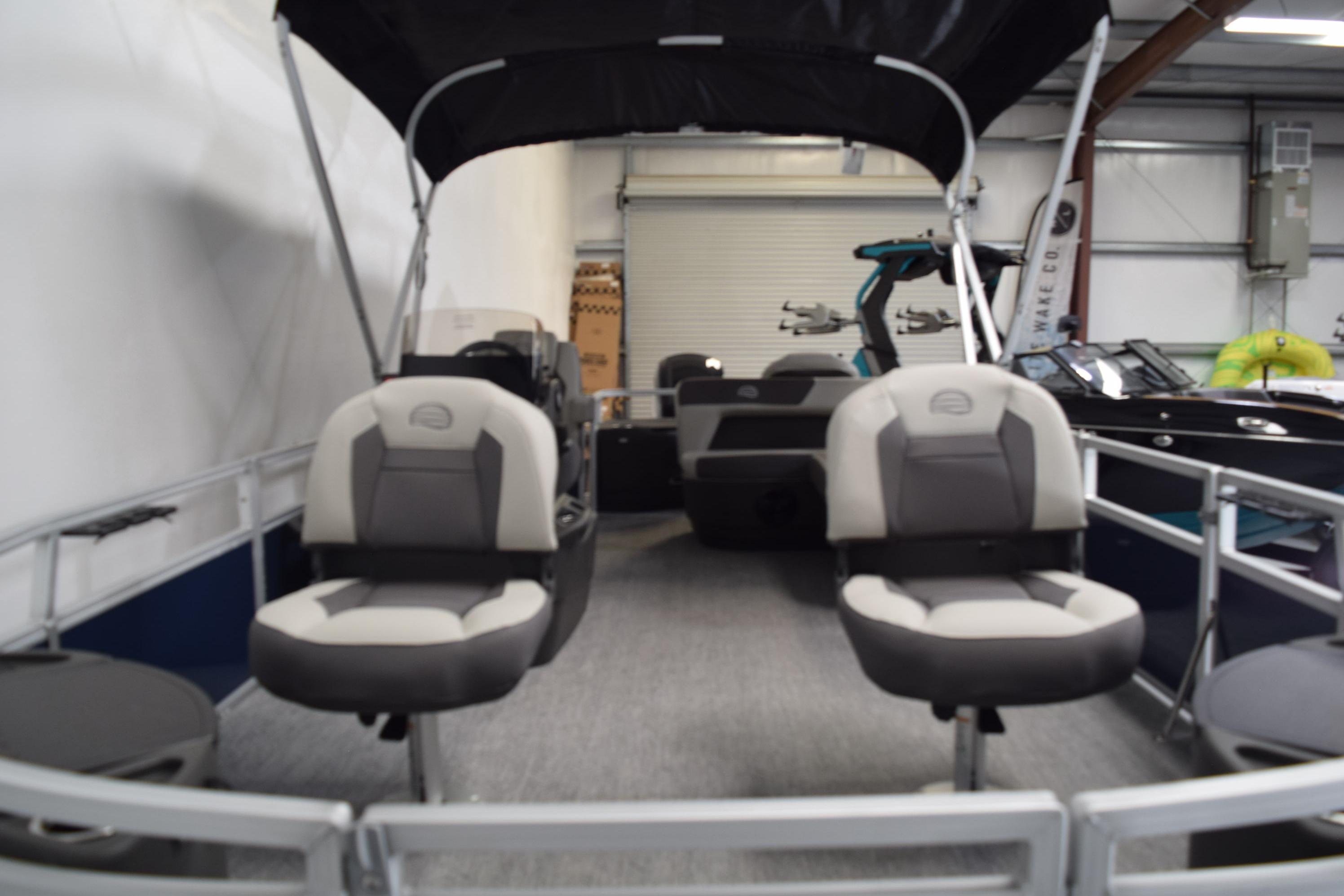 2026 Sun Tracker Bass Buggy 18 DLX interior with seating and canopy in showroom.