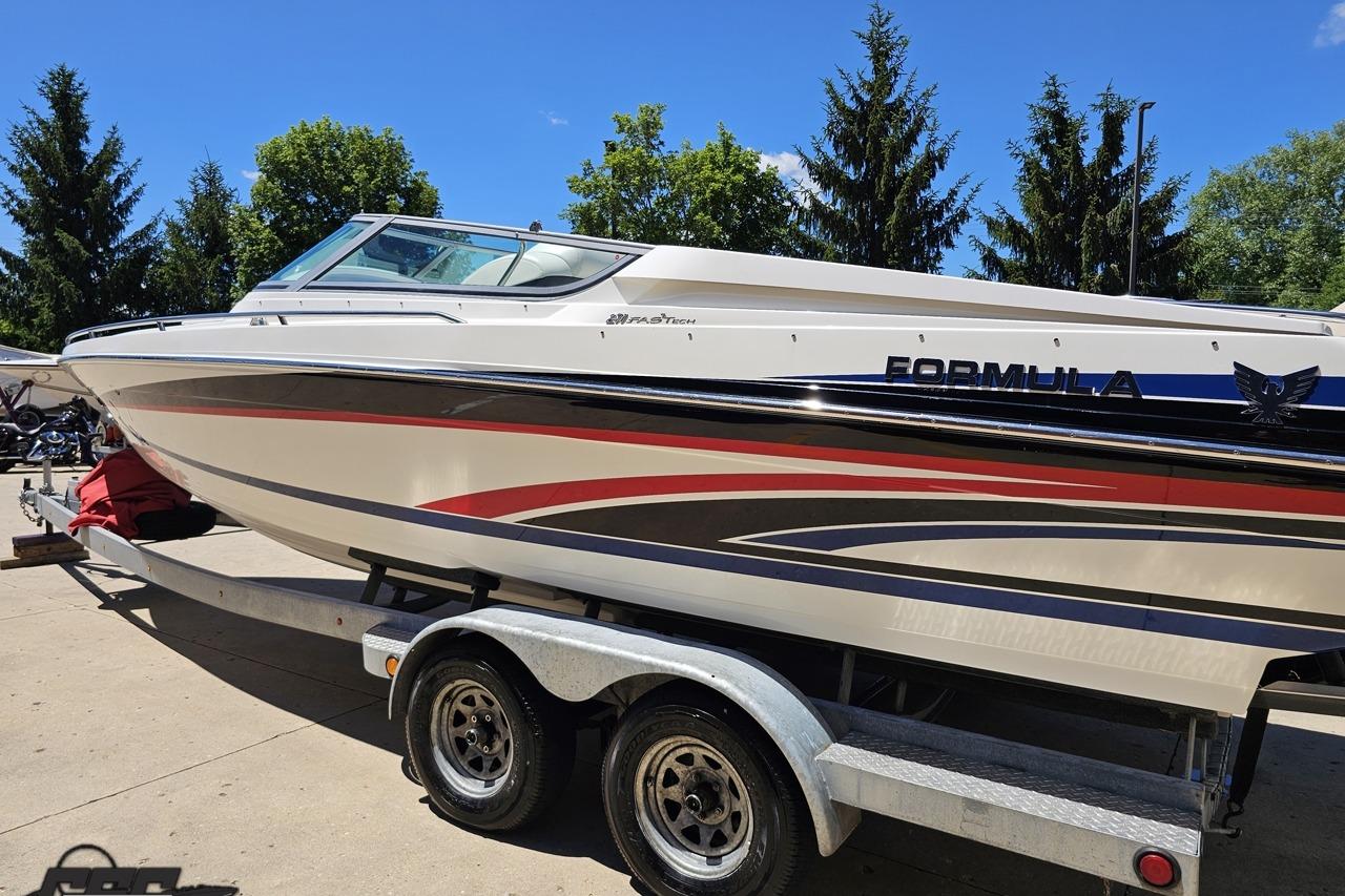 2005 Formula 271 FASTech boat on trailer, sleek design with vibrant graphics, parked outdoors.