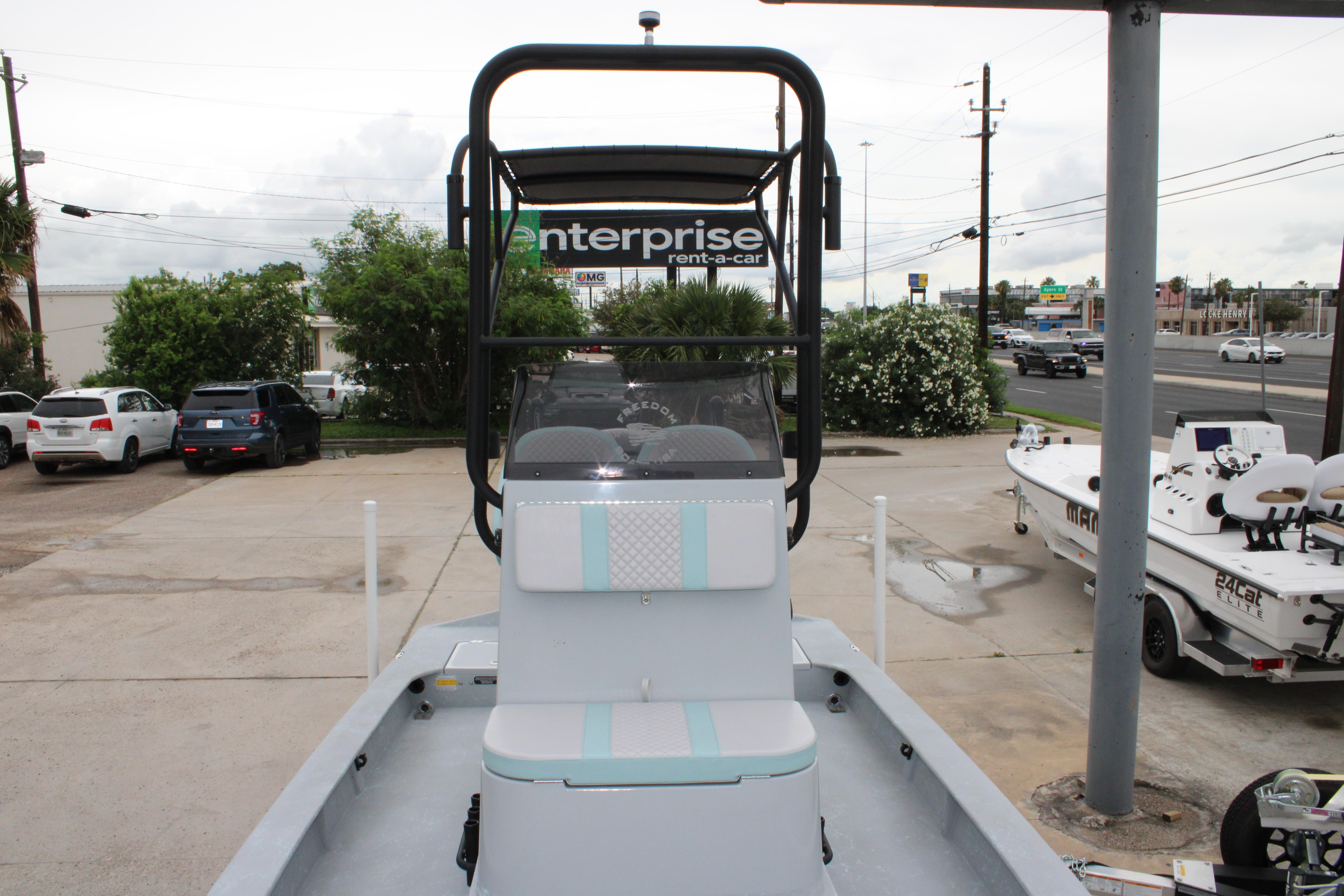 2026 Freedom Boats 24 Defender displayed in a parking lot with nearby vehicles and greenery.