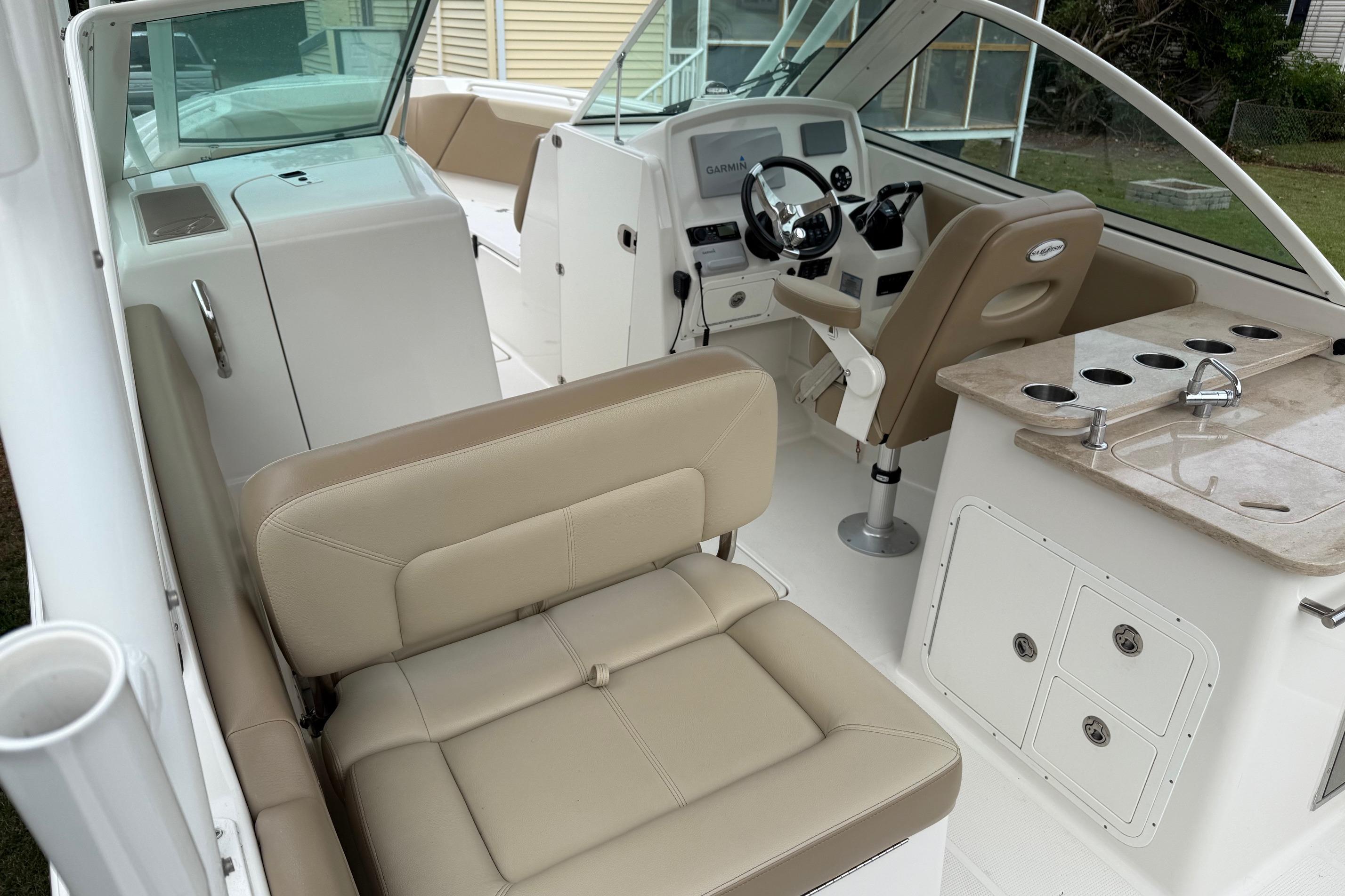 2019 Sailfish 275 DC boat interior with beige seating, steering console, and kitchenette.