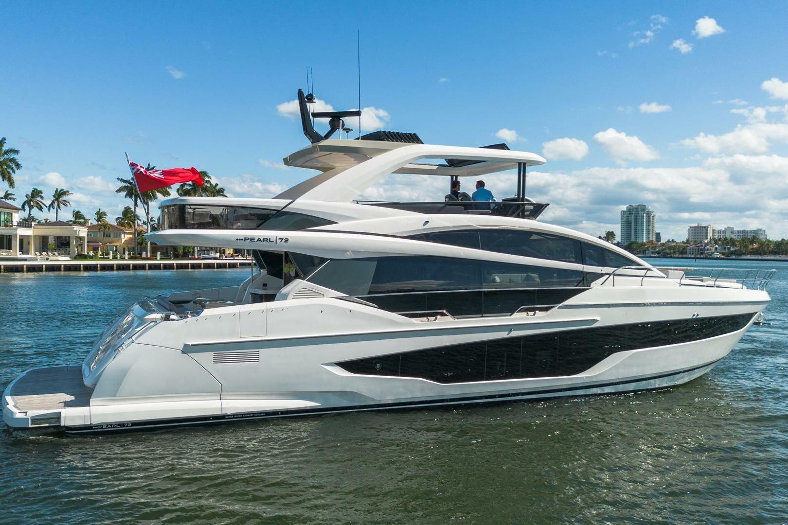 Luxurious 2023 Pearl 72 yacht cruising on a sunny day near waterfront homes.