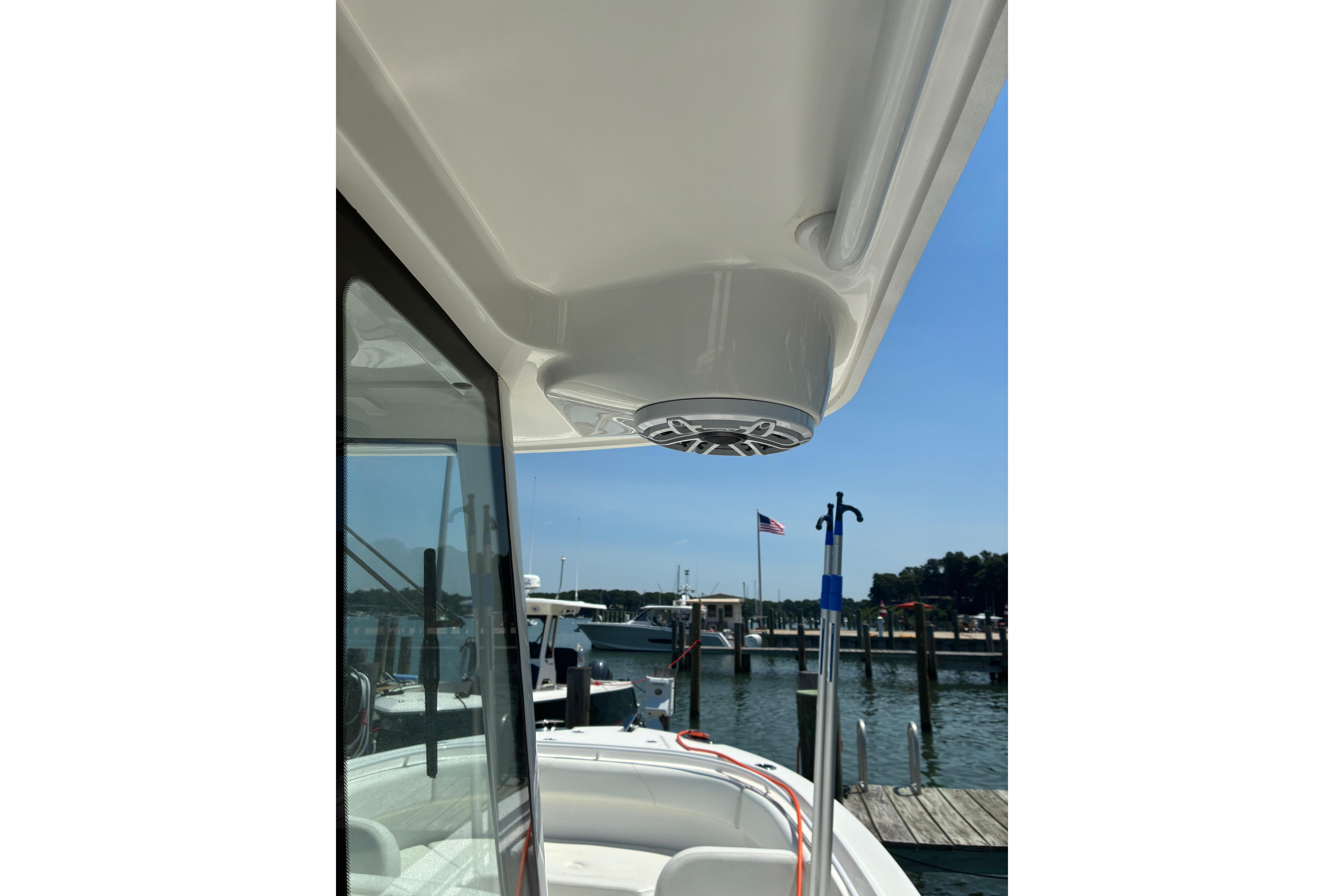 2023 Edgewater 285CC boat with speaker, docked at marina under clear blue sky.
