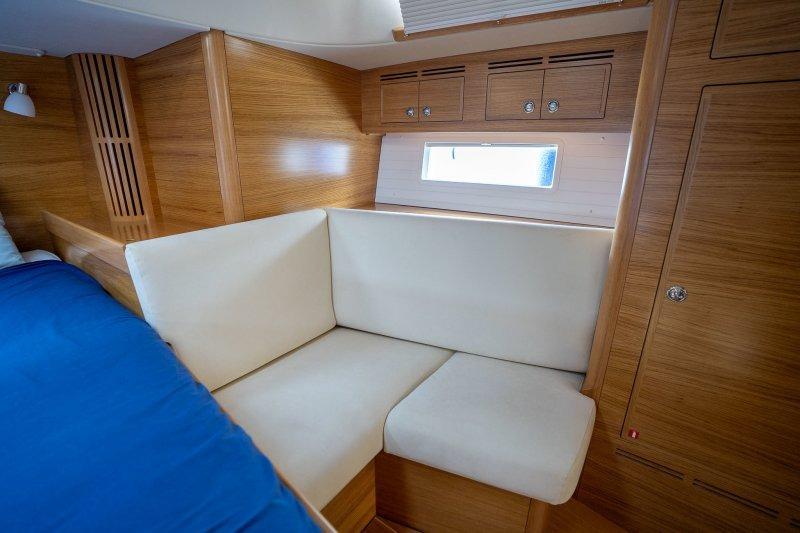 Interior of 2023 Hallberg-Rassy 50 yacht with cozy seating and wooden finish.
